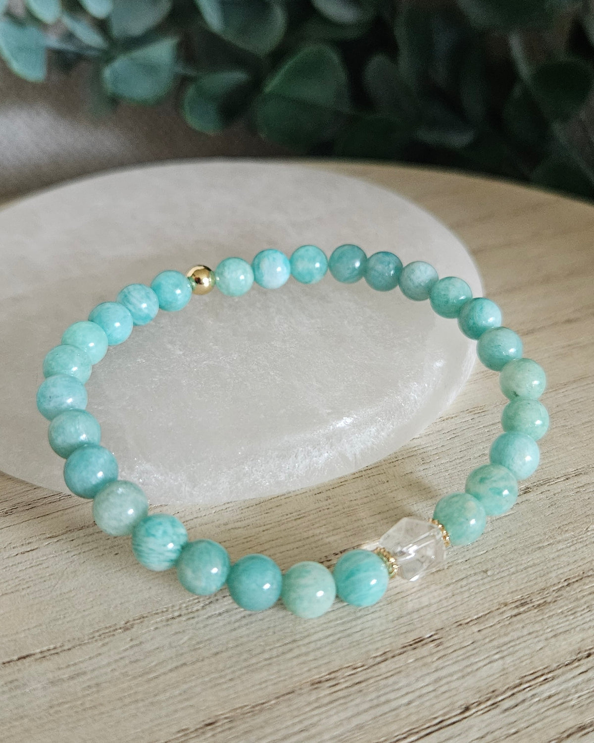 Amazonite Still bracelet with 6mm turquoise gemstone beads, Clear Quartz focal and gold accents styled on selenite with greenery behind it