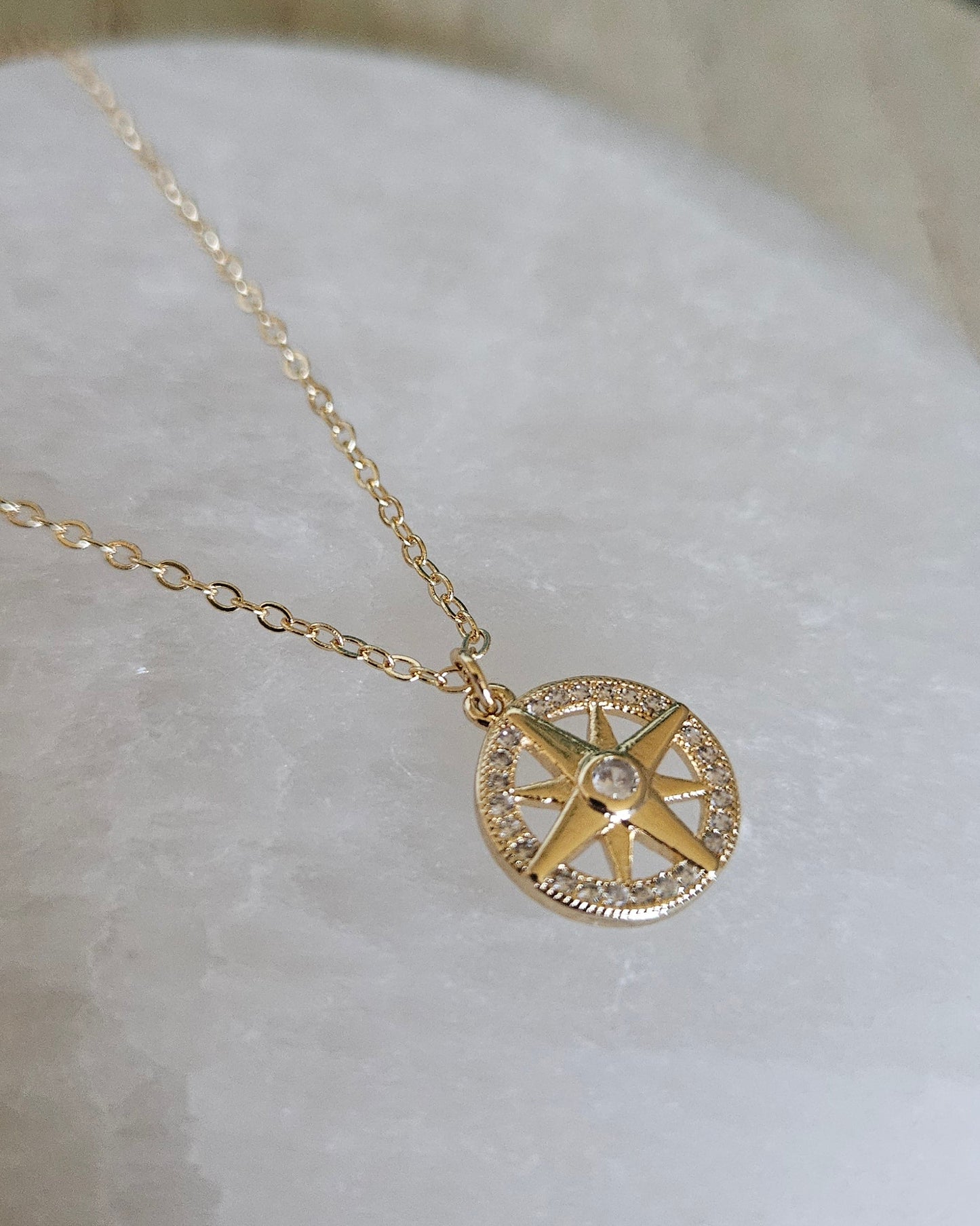 Close-up of the North Star pendant and delicate gold-filled chain displayed on selenite