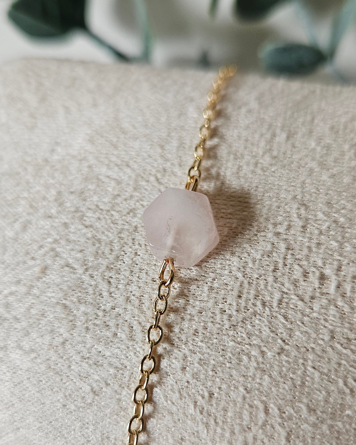 Close view of the Rose Quartz gemstone focal on a fine gold-plated chain bracelet with soft neutral styling