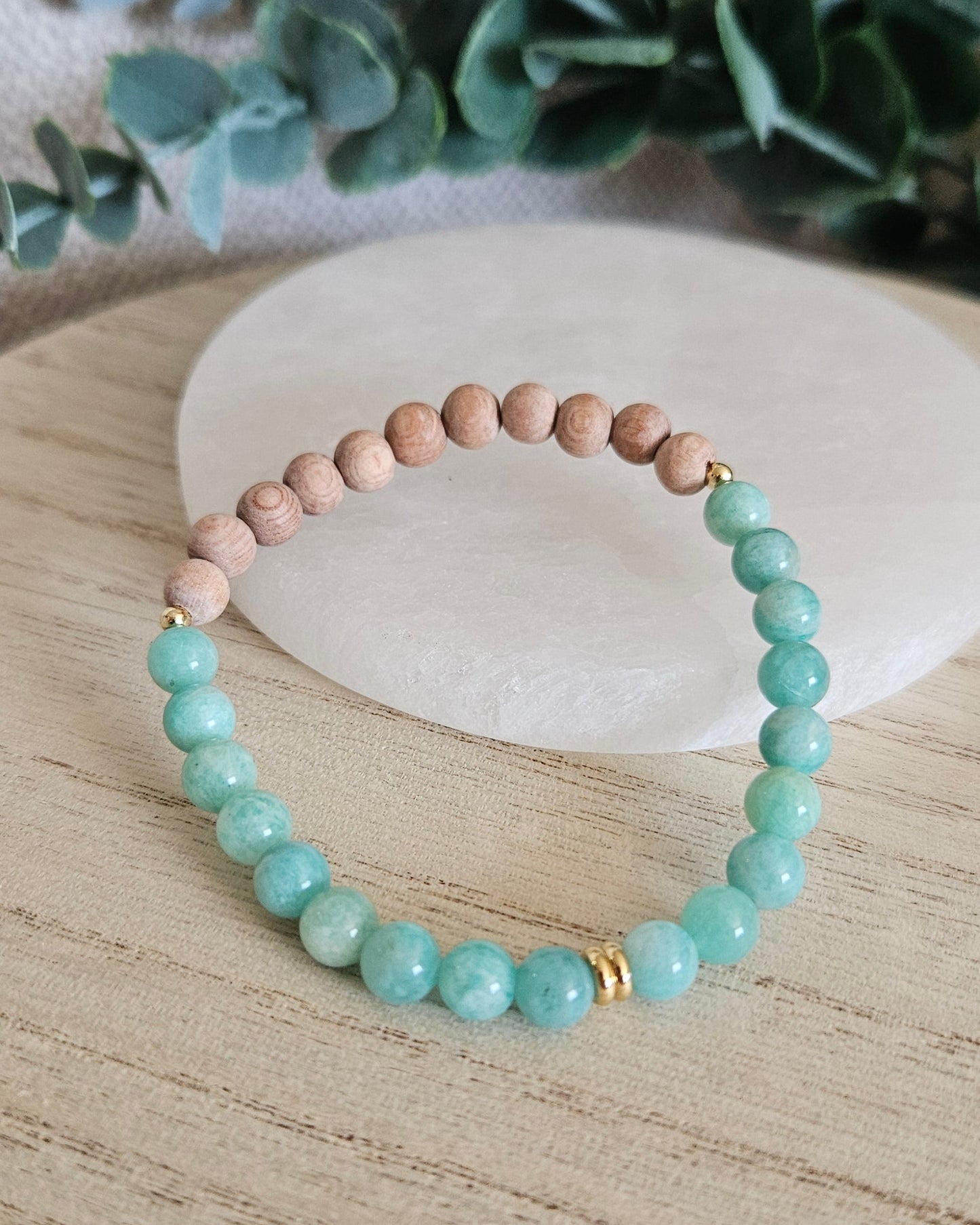 Amazonite and unwaxed Rosewood diffuser bracelet with gold-plated accents displayed beside a selenite plate