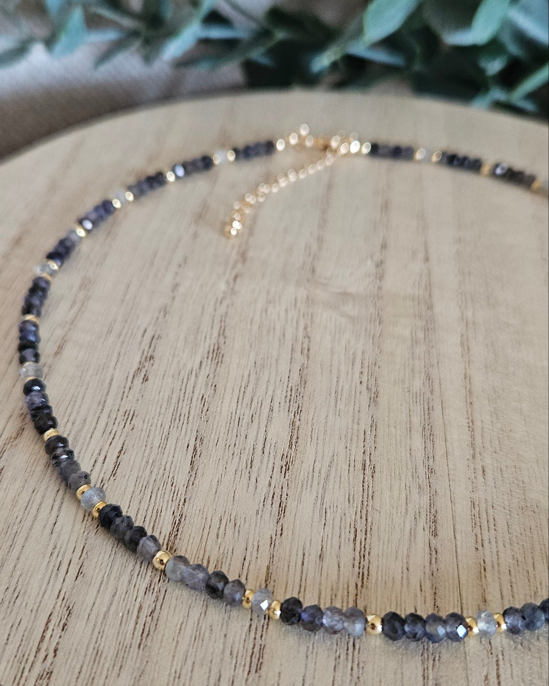 Angled close view of the Iolite and Labradorite necklace with its gold-plated extender chain in the background