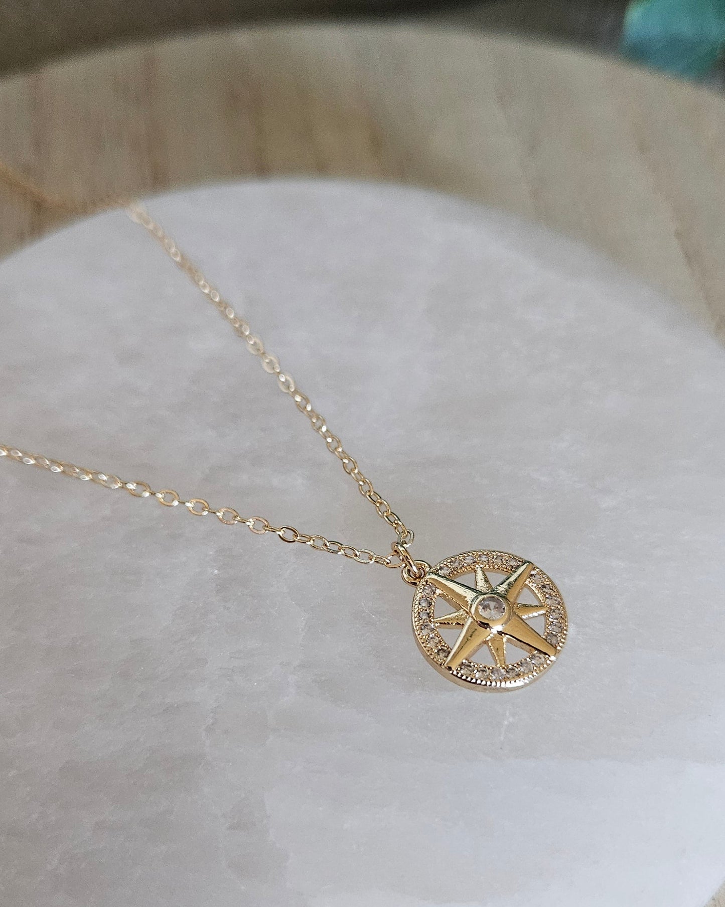 Angled view of the North Star necklace and cubic zirconia pendant resting on a round selenite plate