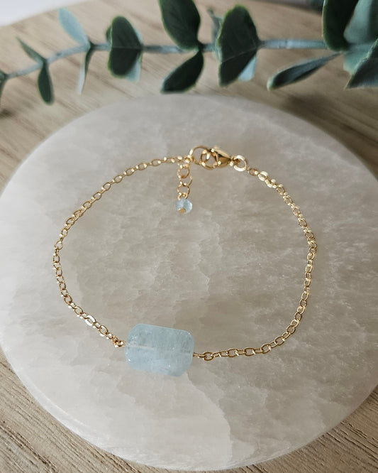 Aquamarine Whisper bracelet laid flat on a selenite plate with 14k gold-plated chain, clasp and extender