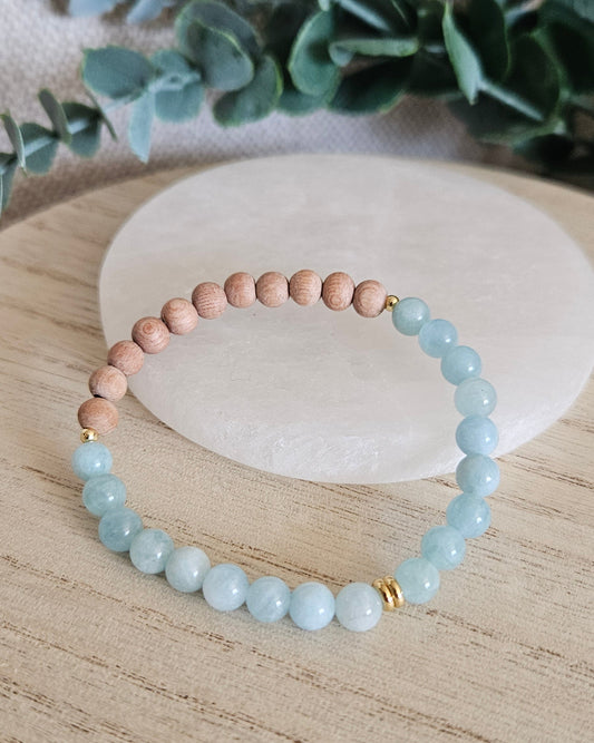 Aquamarine and unwaxed Rosewood diffuser bracelet with gold-plated accents displayed beside a selenite plate