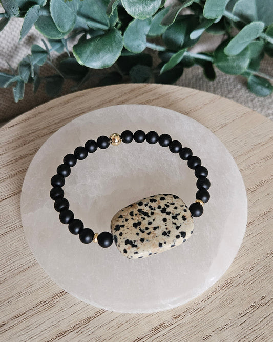 Overhead view of the matte Black Onyx bracelet with a large speckled Dalmatian Jasper focal on selenite