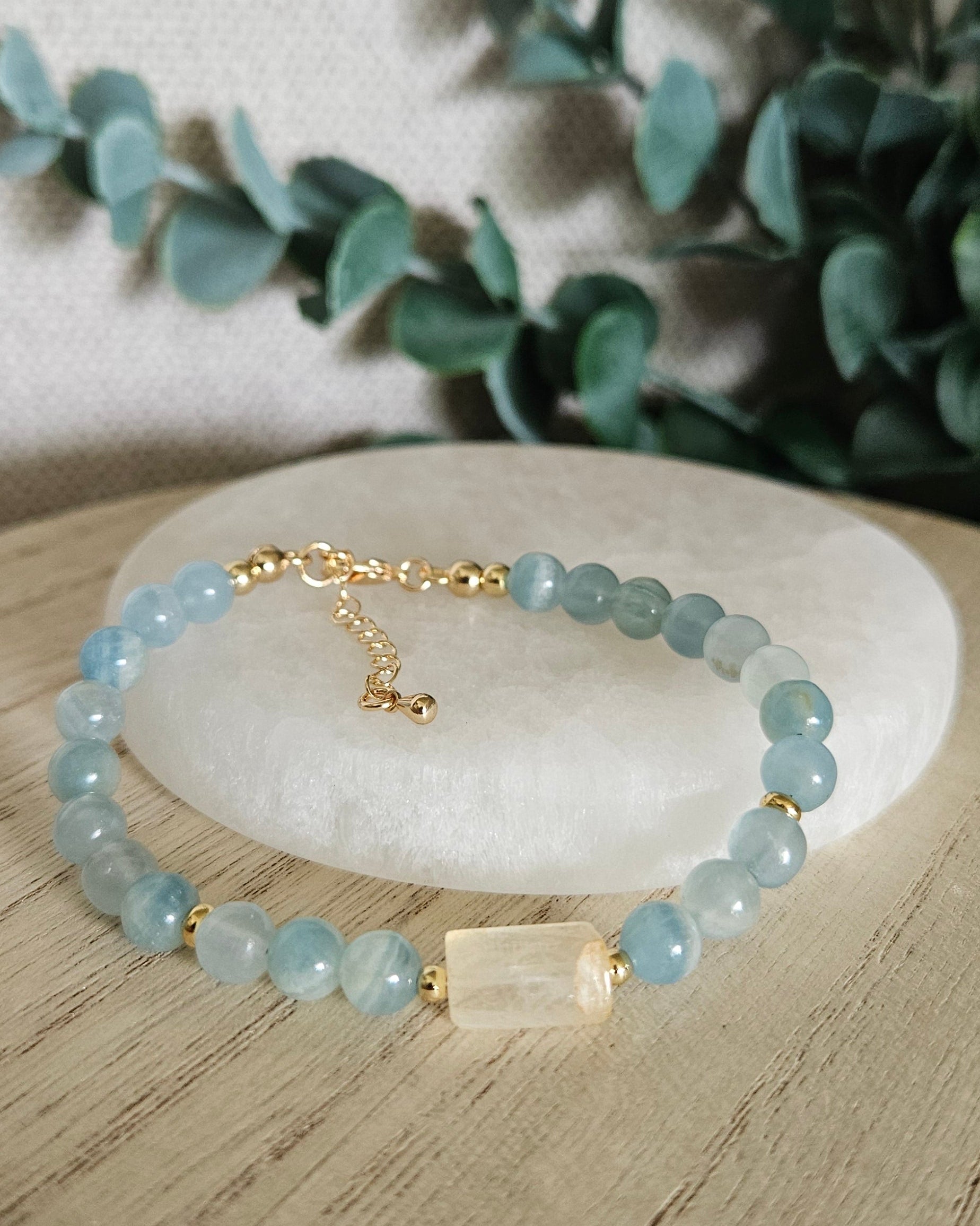 Blue Calcite and Citrine bracelet arranged before a selenite plate with eucalyptus in the background