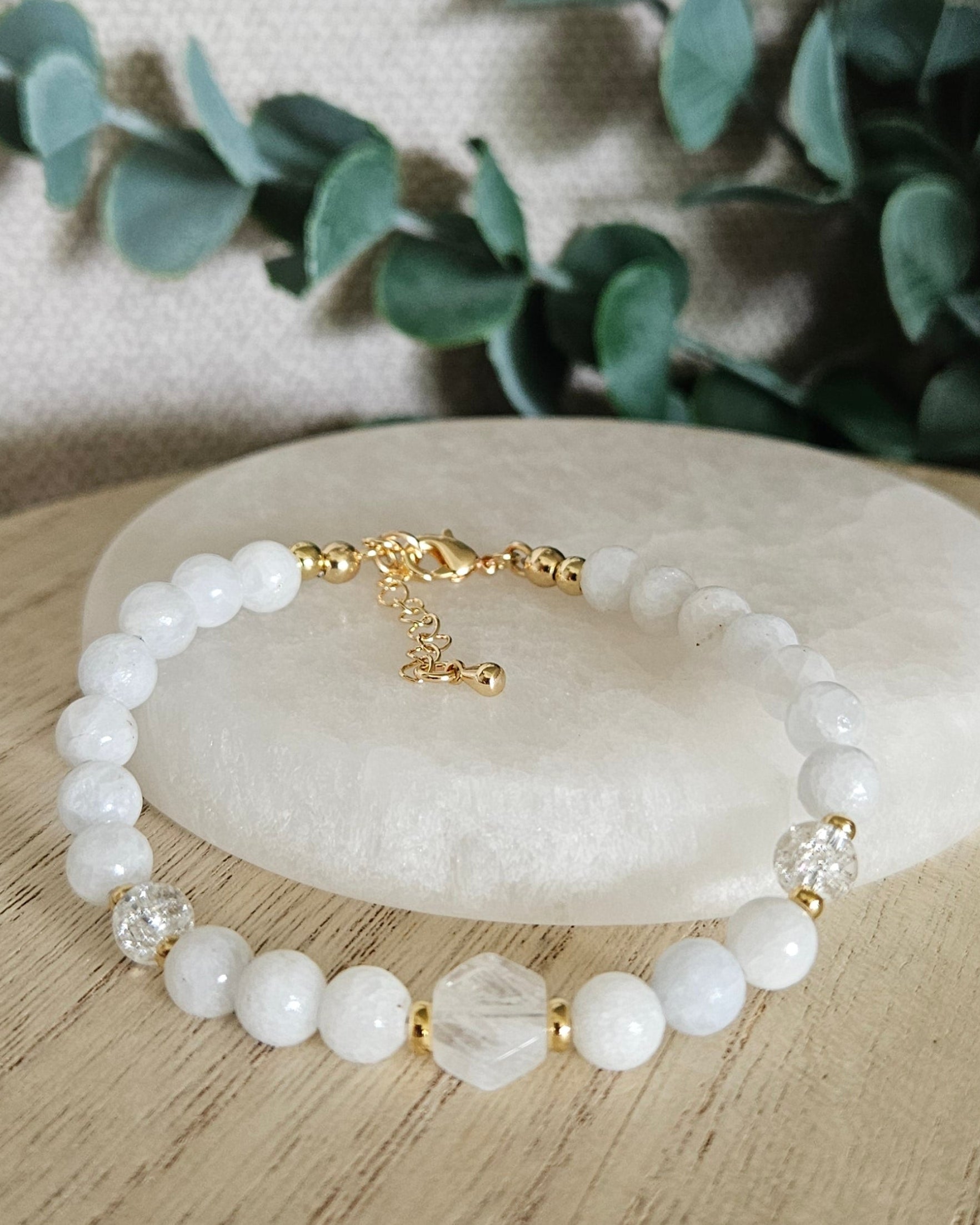 Celestite, Moonstone and Cracked Quartz bracelet arranged before a selenite plate with eucalyptus in the background