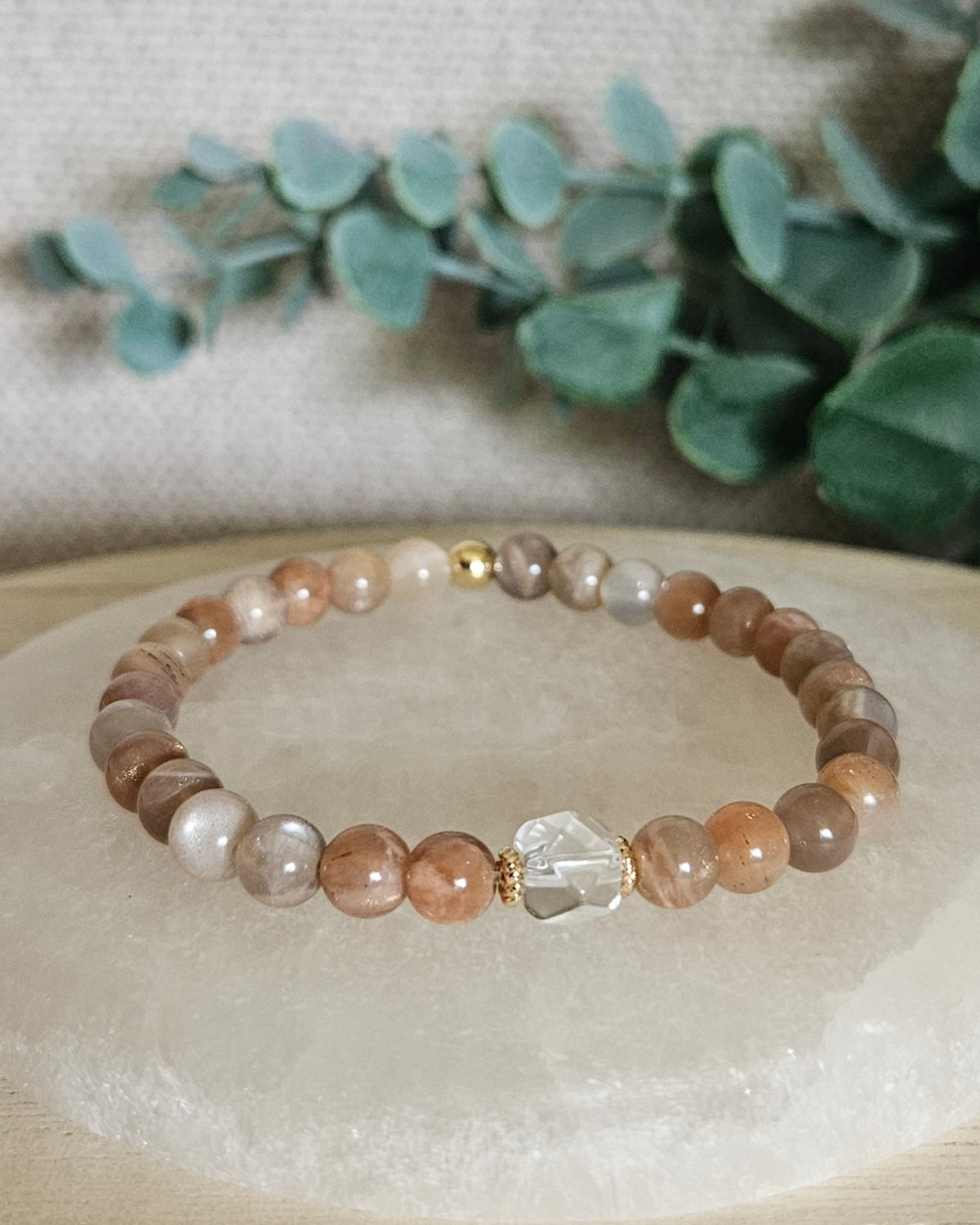 Chocolate Moonstone Still bracelet with 6mm peach, brown and cream gemstone beads, Clear Quartz hexagon focal and 14k gold-plated accents displayed on selenite