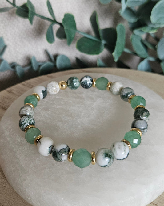 Close-up of Green Aventurine and Tree Agate bracelet with gold-plated accents beside leafy greenery