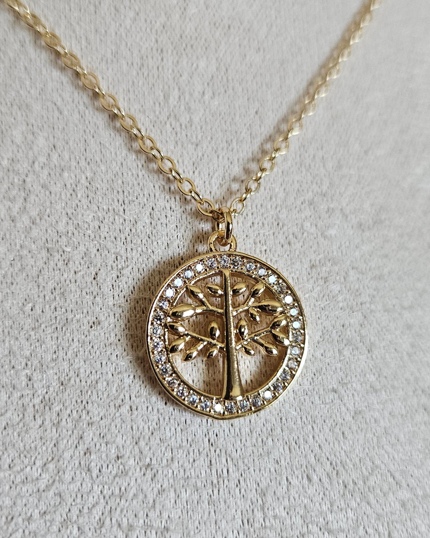 Close-up of the gold Tree of Life pendant framed by circular cubic zirconia detailing