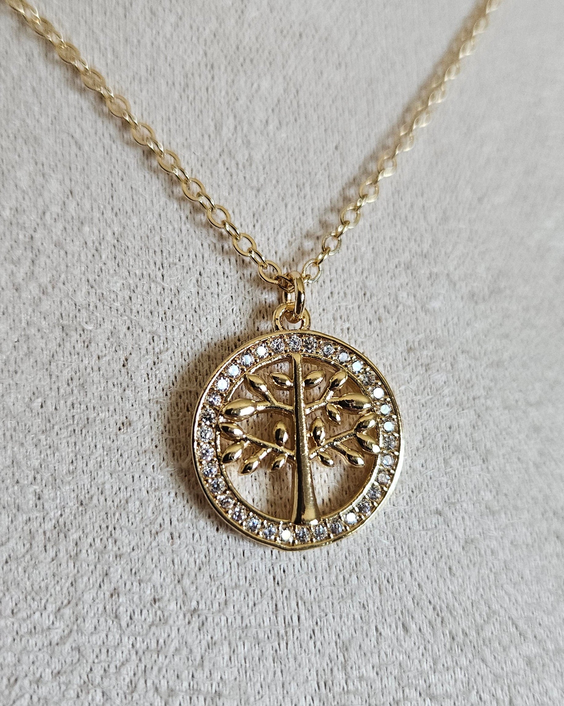Close-up of the gold Tree of Life pendant framed by circular cubic zirconia detailing