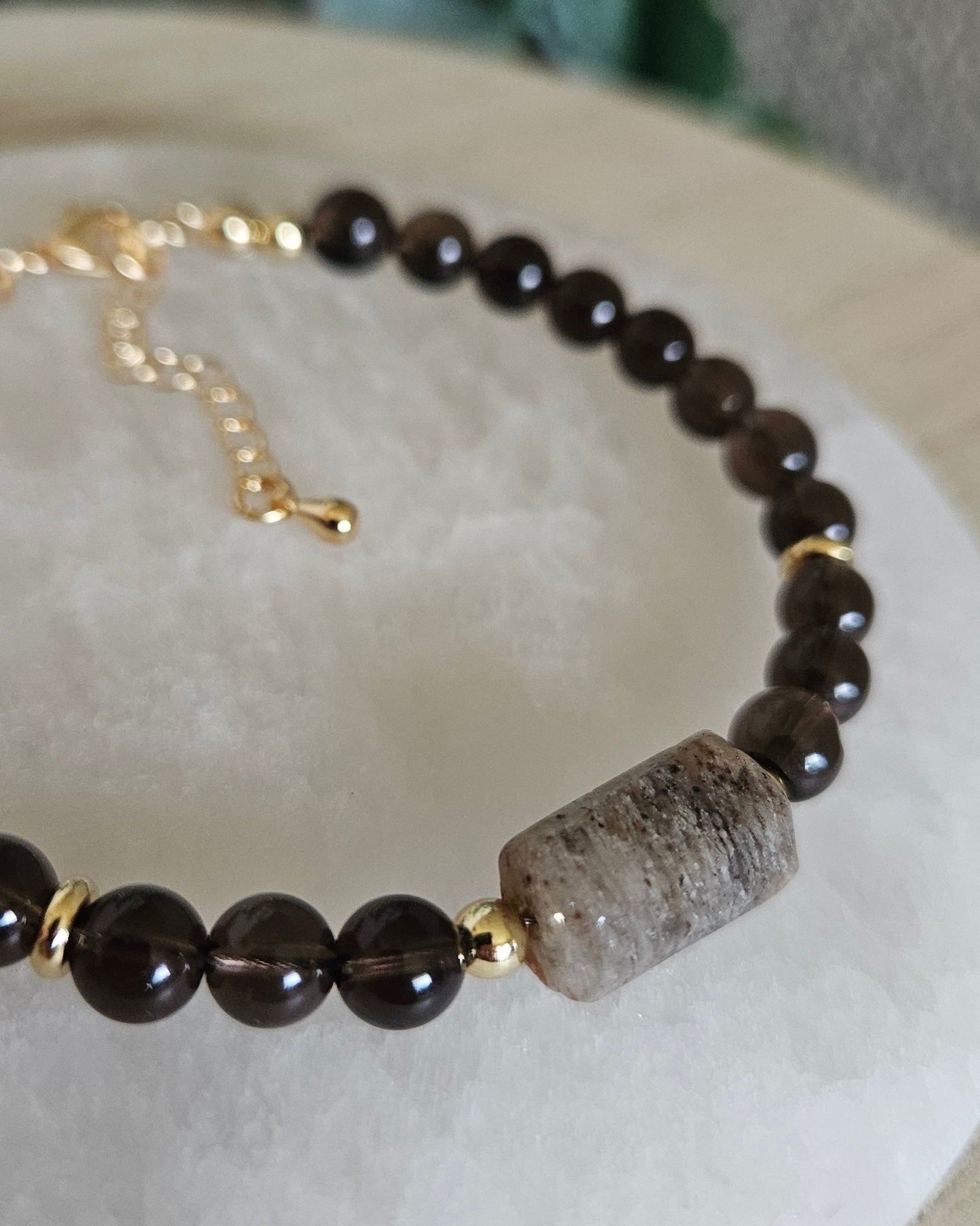 Close-up of the layered inclusions in the Angel Phantom Quartz focal beside translucent Smoky Quartz beads