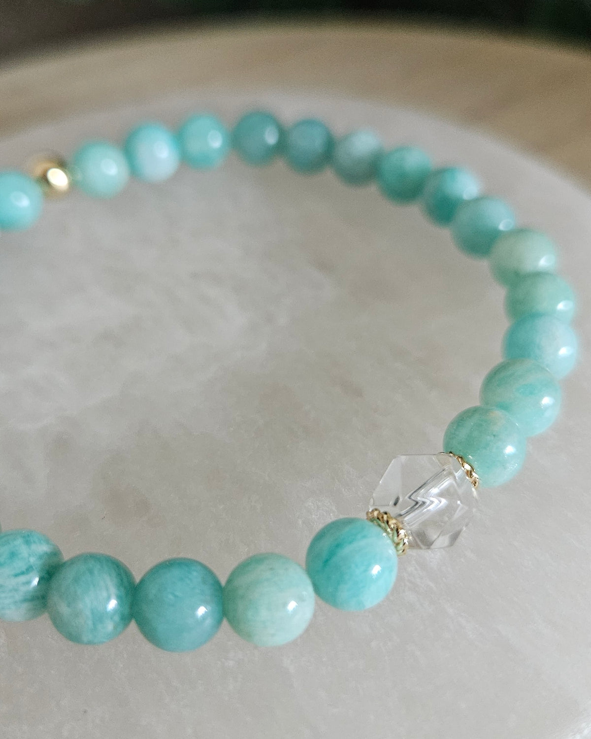 Close view of Amazonite beads with soft blue-green colour, Clear Quartz hexagon focal and 14k gold-plated spacers on selenite