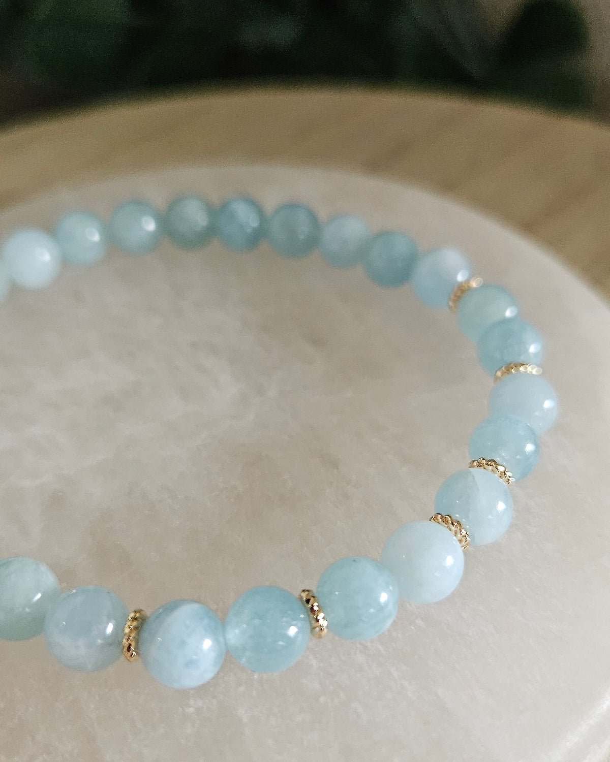 Close view of Aquamarine beads with pale blue tones and 14k gold-plated spacer accents on selenite