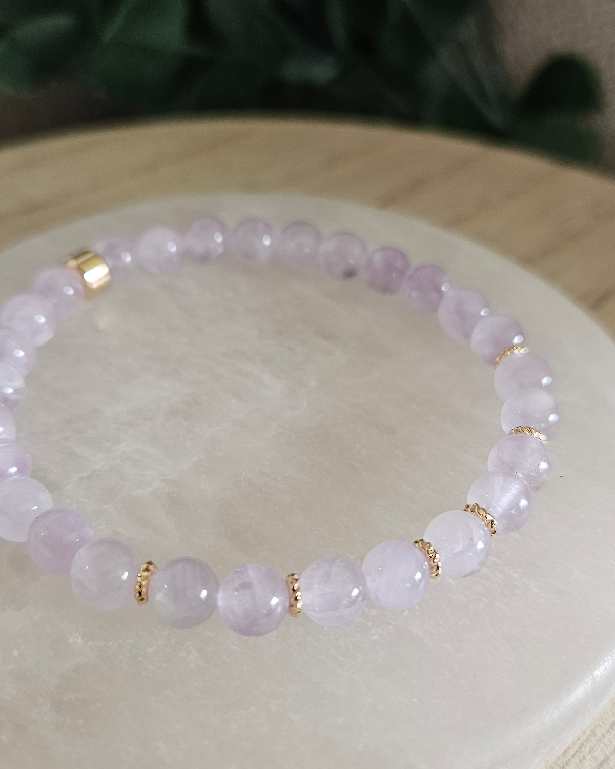 Close view of Lavender Amethyst beads with soft purple tones and 14k gold-plated details on a white selenite display