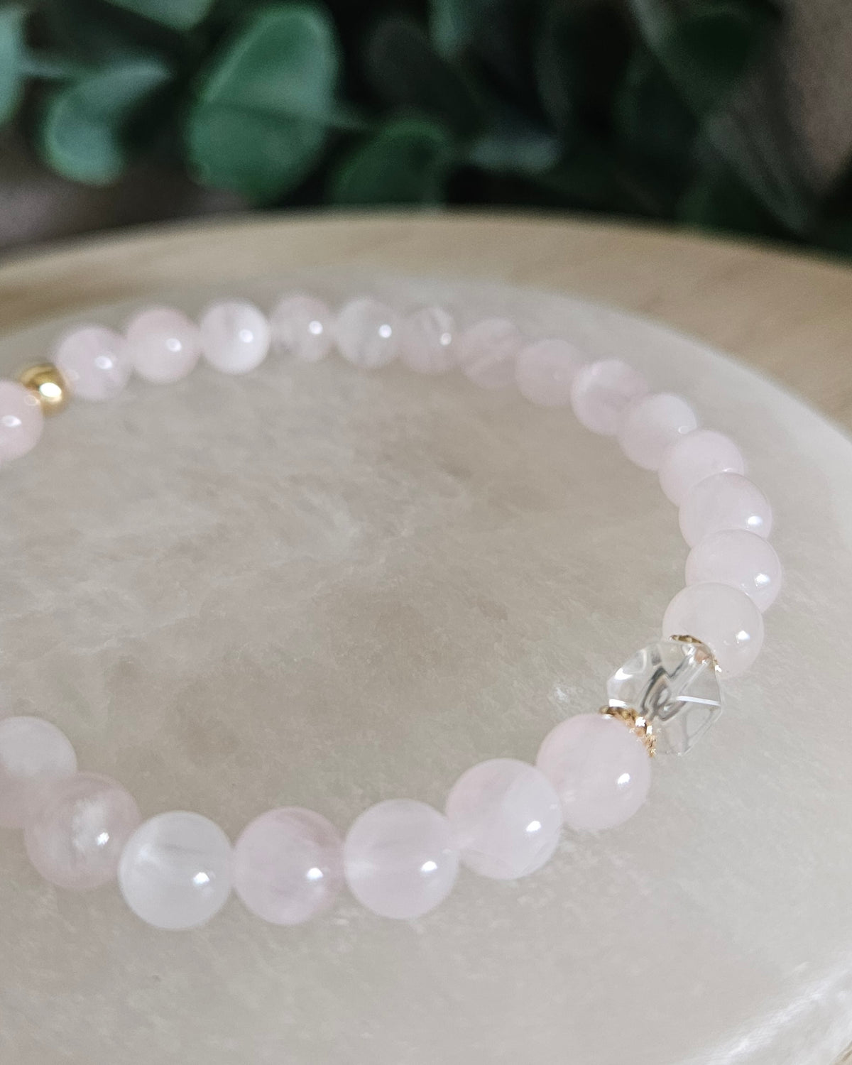 Close view of Rose Quartz beads with soft pink tones, Clear Quartz hexagon focal and 14k gold-plated spacers on selenite
