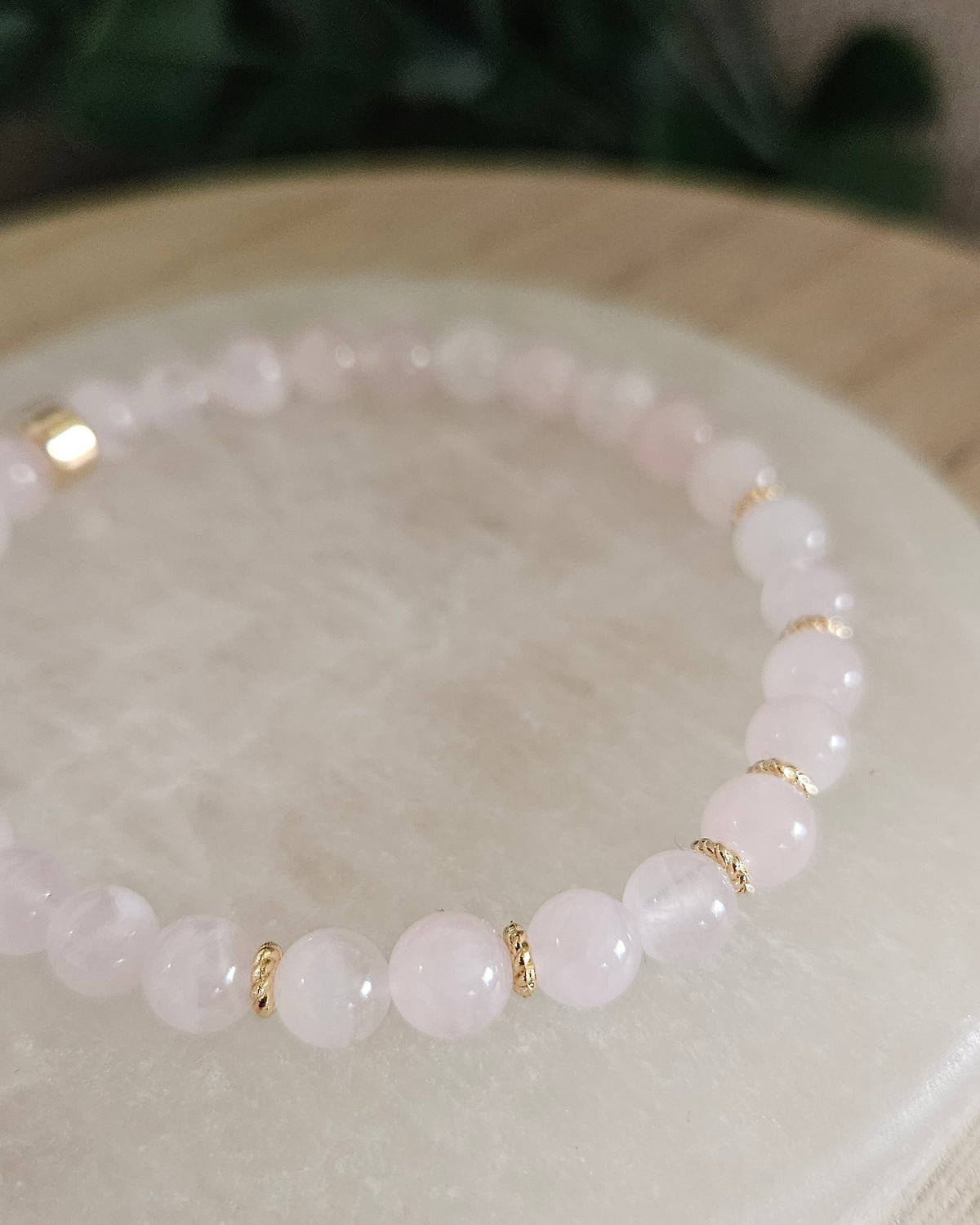 Close view of Rose Quartz beads with pale pink tones and 14k gold-plated spacer accents on selenite