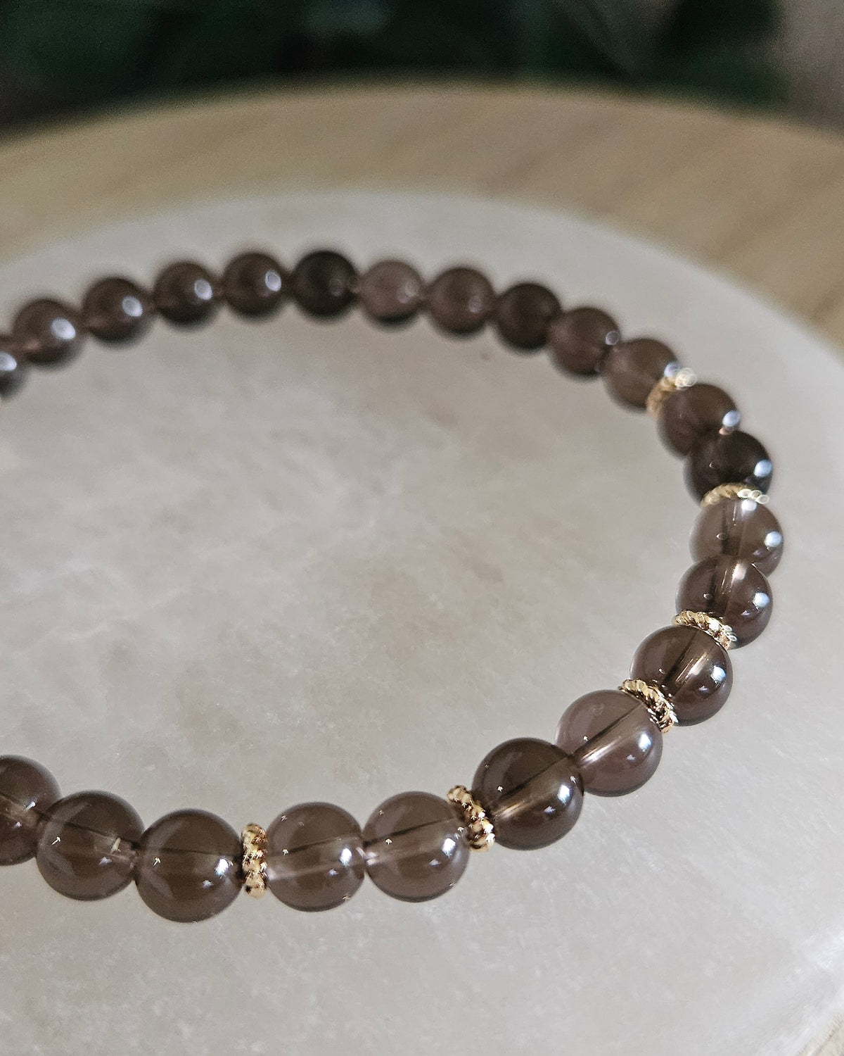 Close view of Smoky Quartz beads with warm brown tones and 14k gold-plated spacer accents on selenite