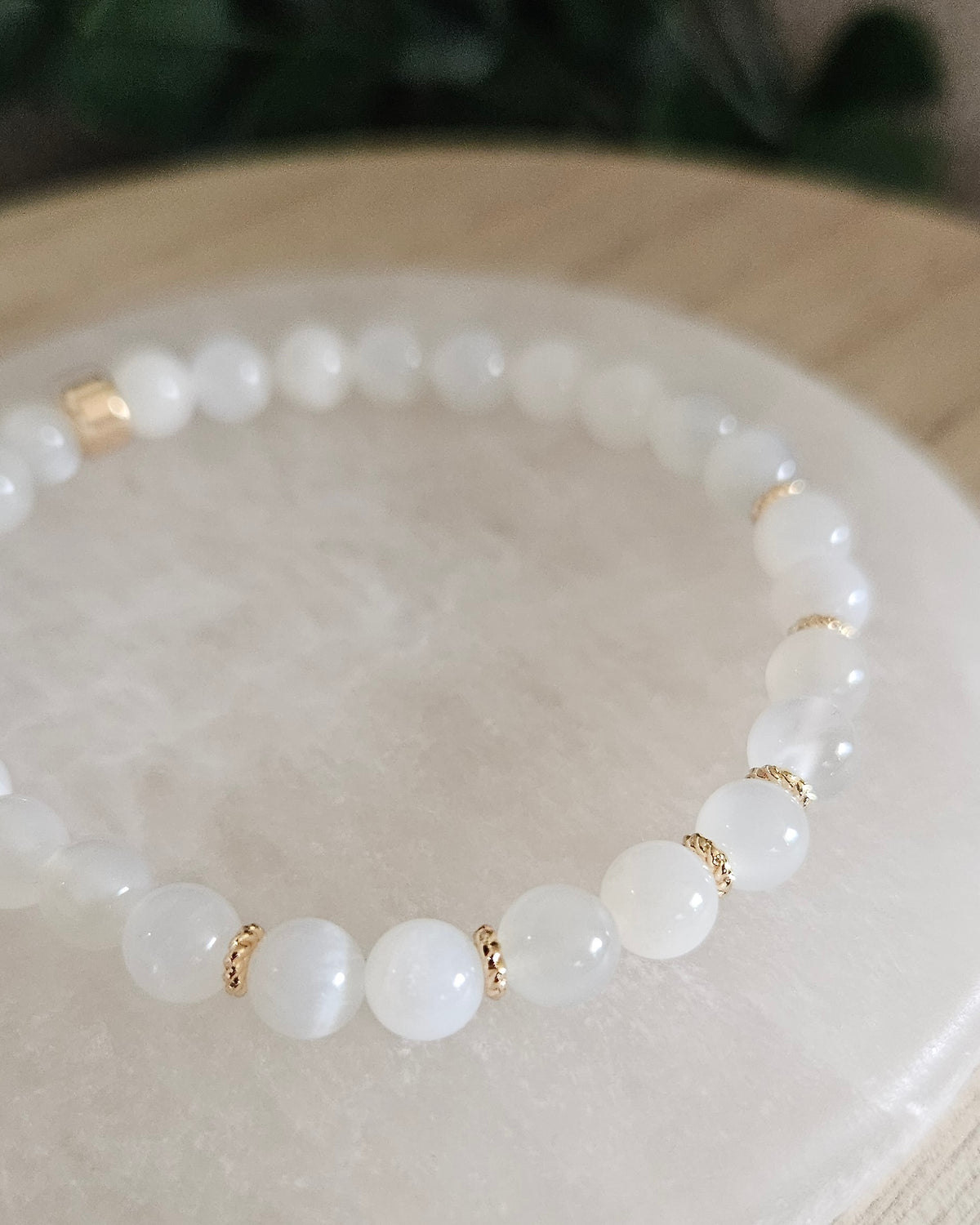 Close view of White Moonstone beads with creamy tones and 14k gold-plated spacer accents on selenite