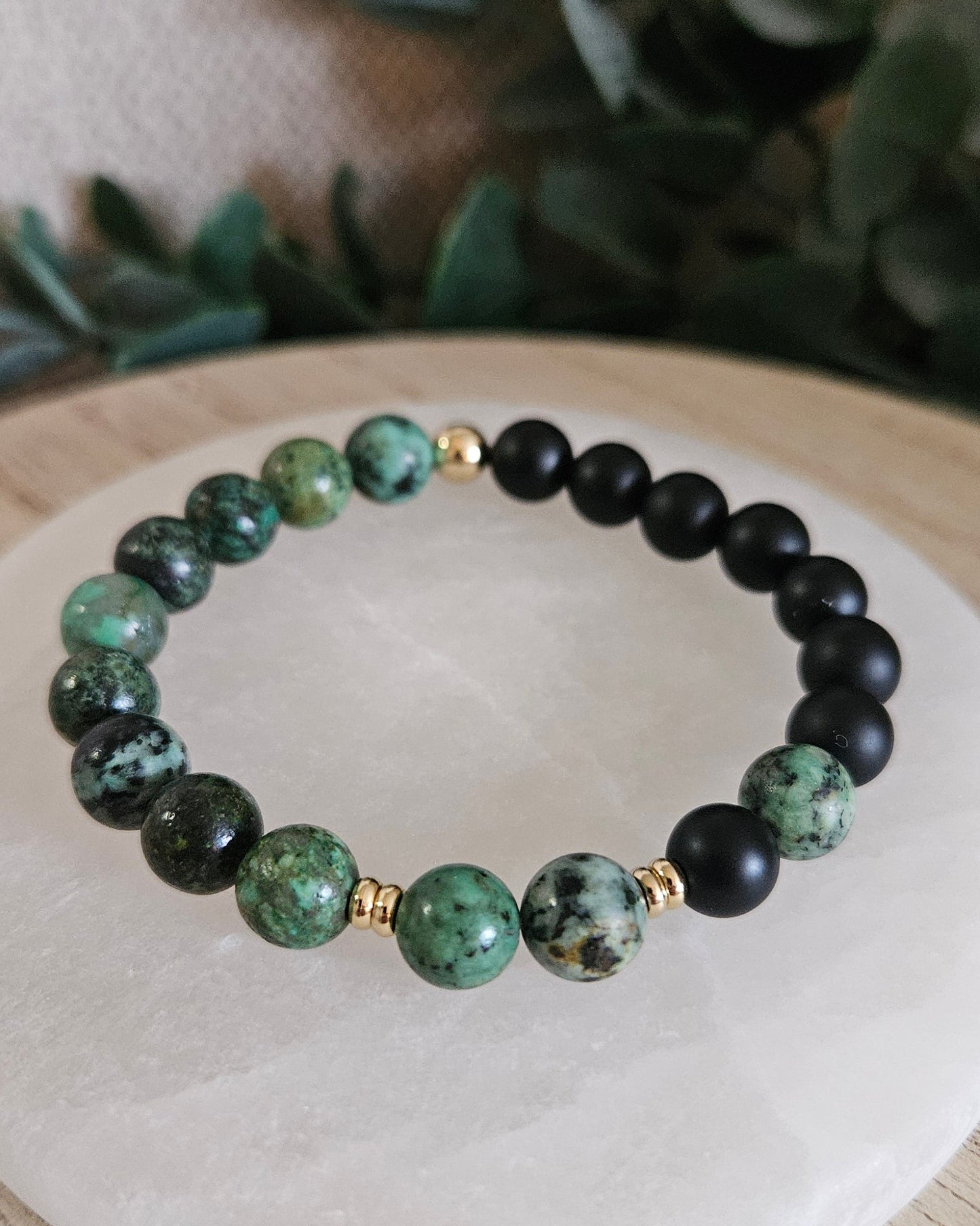 Close view of green African Turquoise and matte Black Onyx beads with polished gold-plated spacer accents