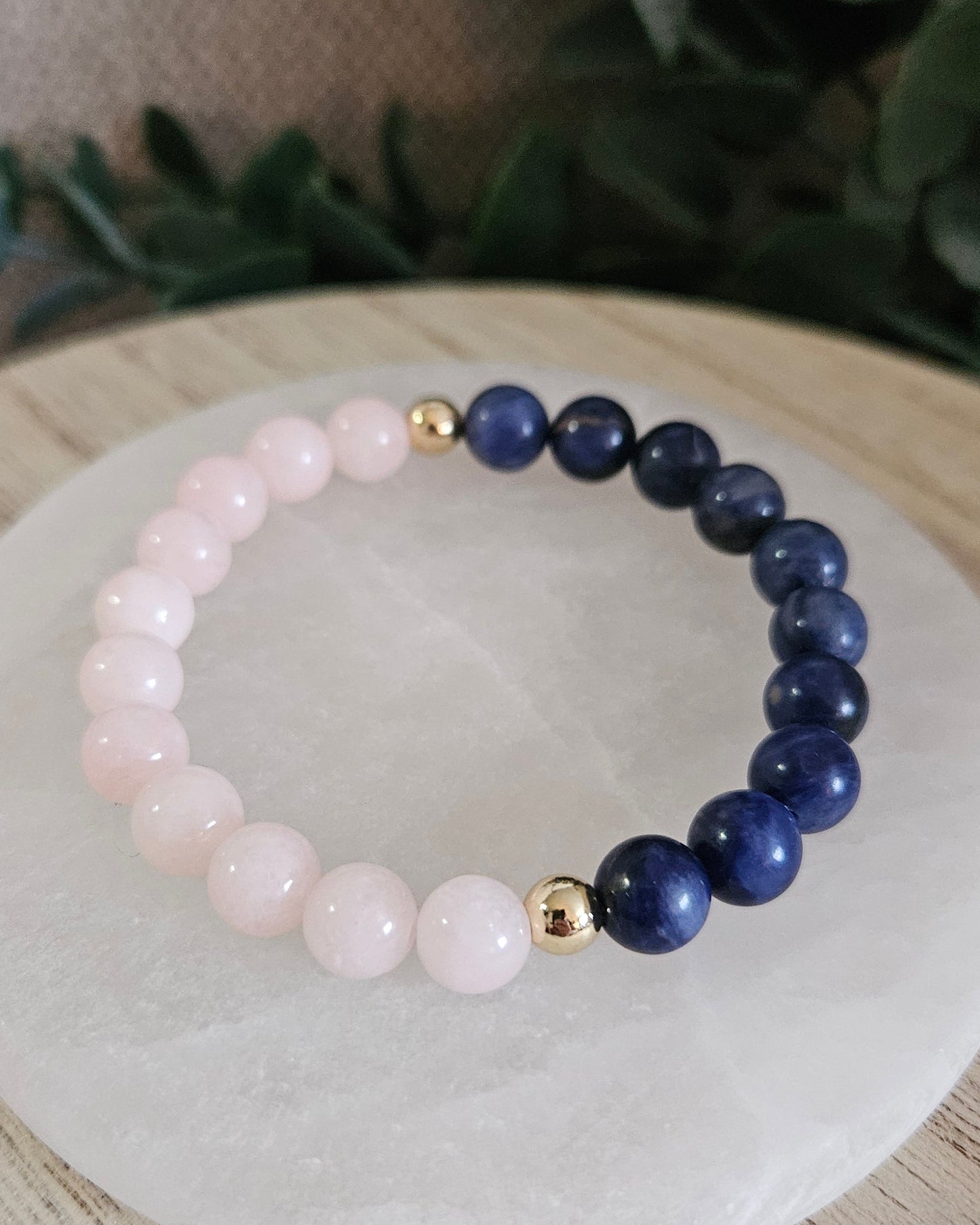 Close view of polished Peach Jade and Sodalite beads separated by two gold-plated accent beads