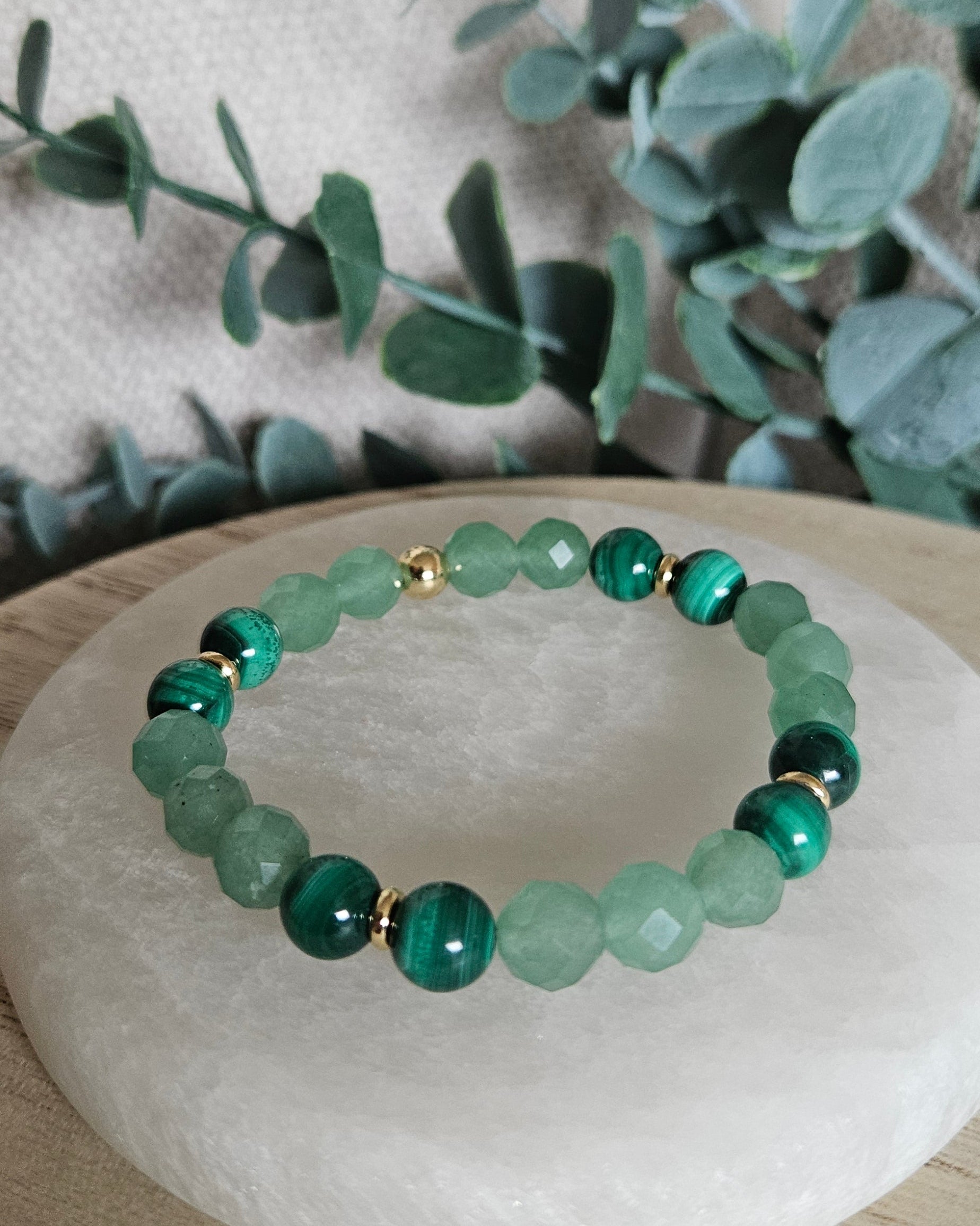 Faceted Green Aventurine and banded Malachite stretch bracelet with gold-plated accents displayed on selenite