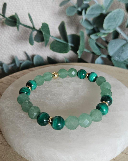 Faceted Green Aventurine and banded Malachite stretch bracelet with gold-plated accents displayed on selenite
