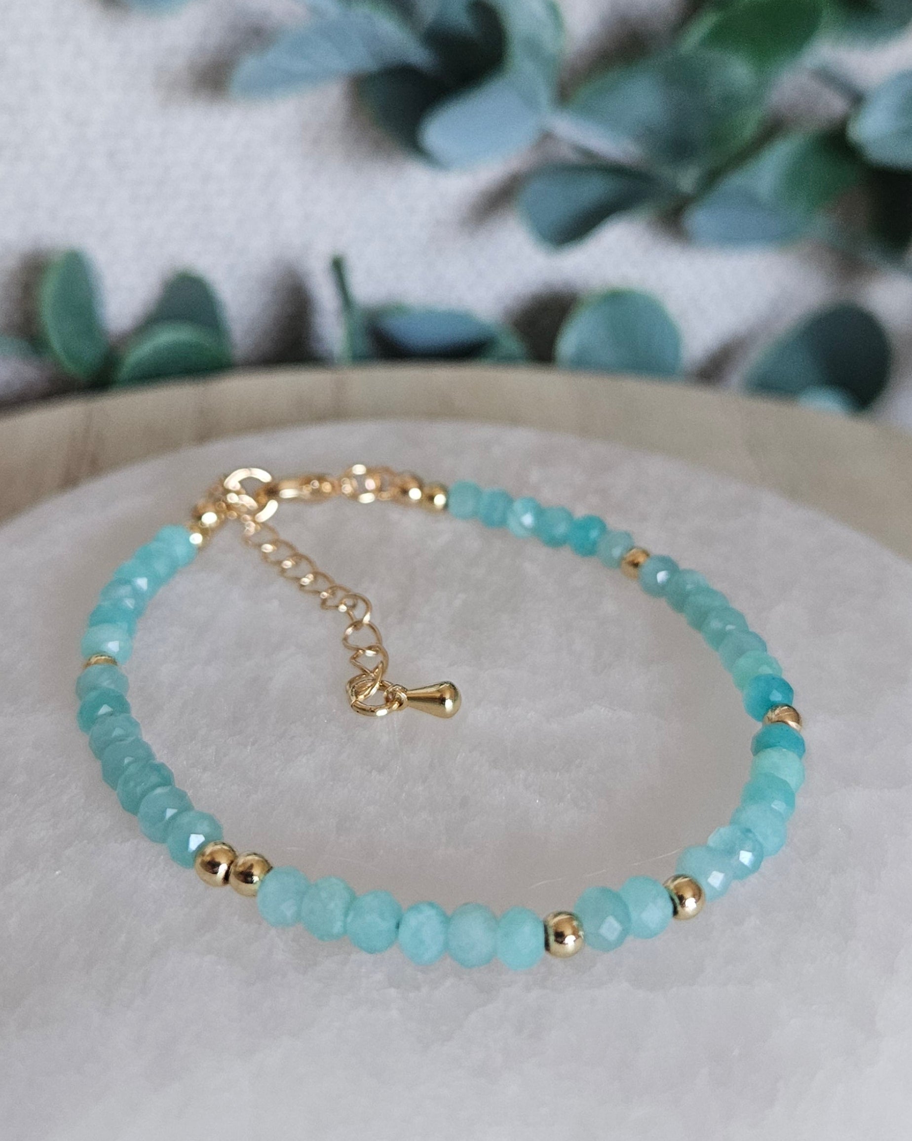 Faceted Mozambique Amazonite bracelet with gold-plated accents, clasp and extender chain displayed on selenite
