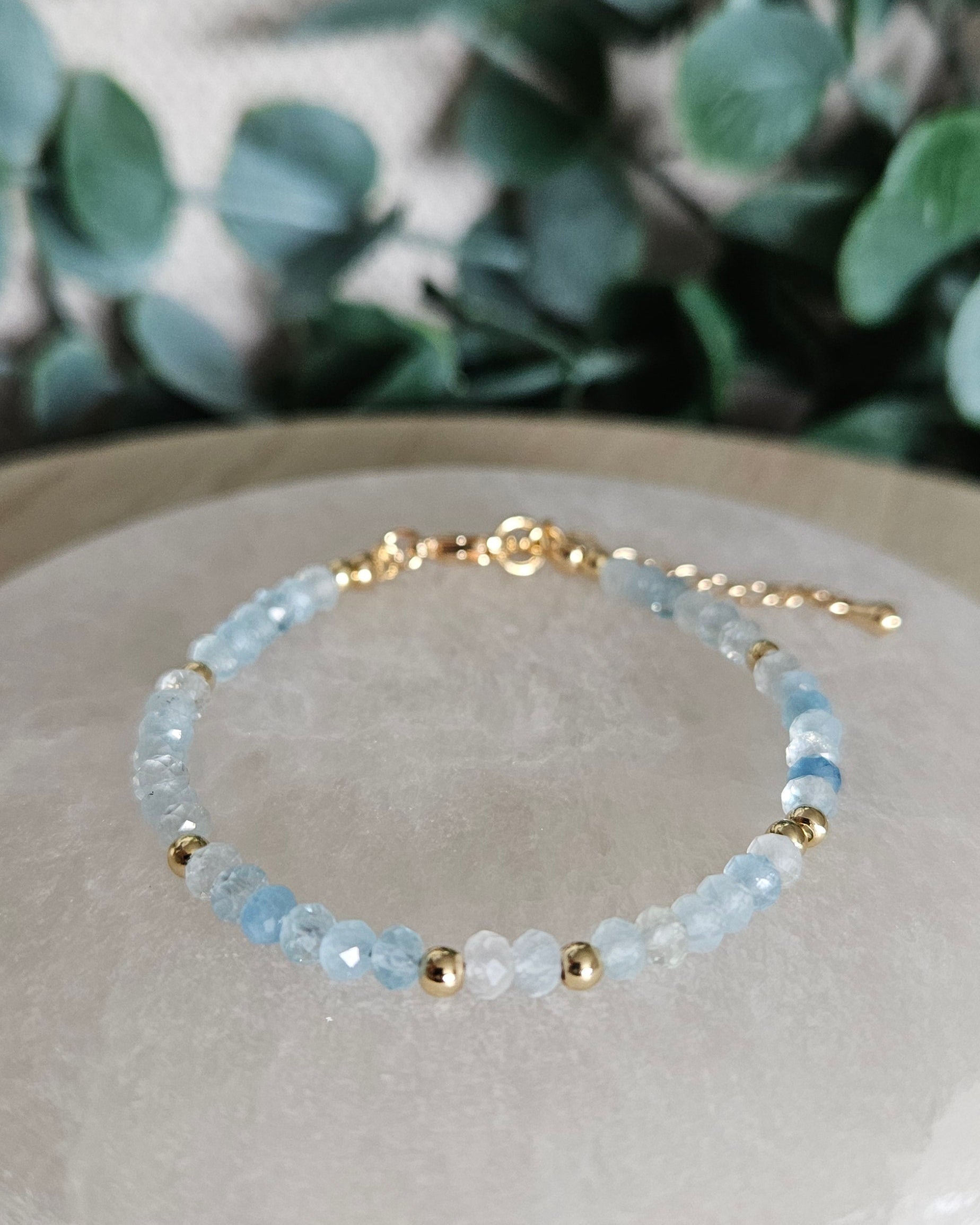Faceted pale-blue Aquamarine bracelet with gold-plated accents, clasp and extender chain displayed on selenite