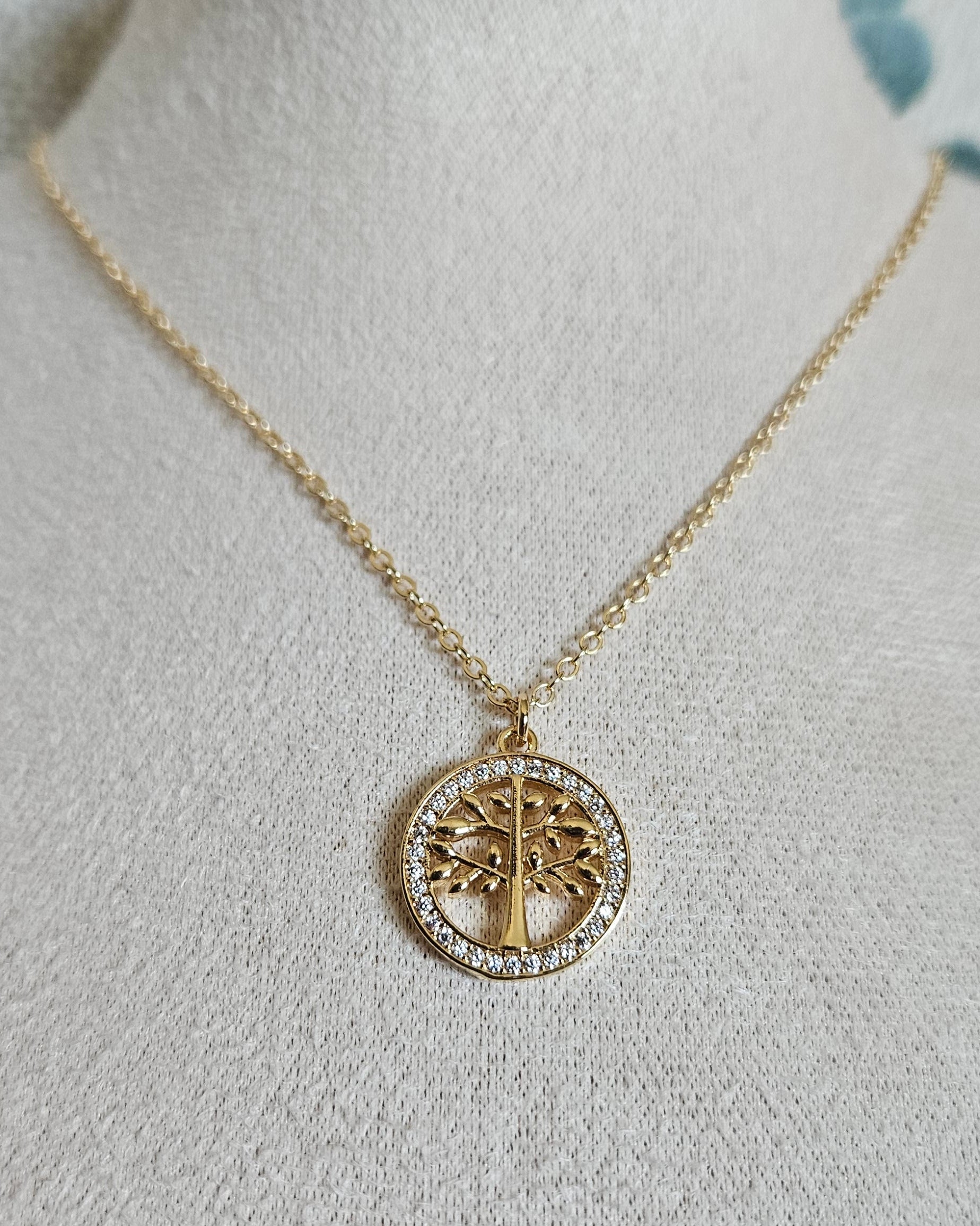Front view of the Tree of Life necklace with a cubic zirconia pendant displayed on a beige jewellery bust