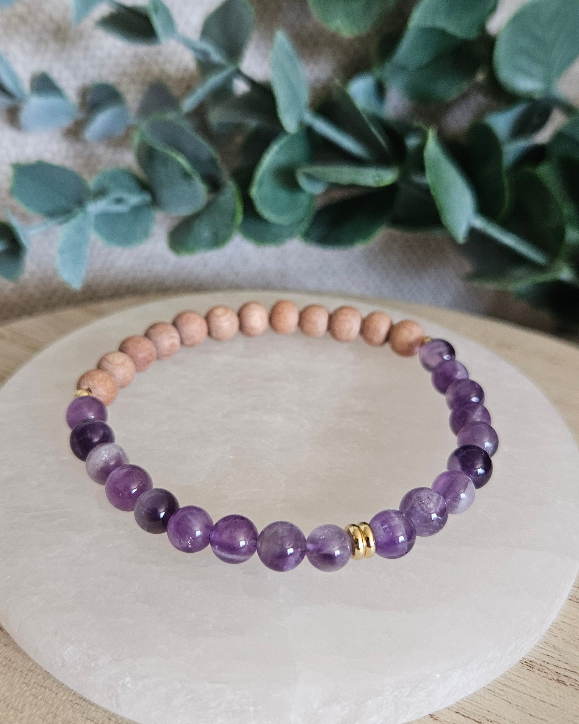 Front view of the purple Amethyst and Rosewood stretch bracelet arranged on a round selenite plate