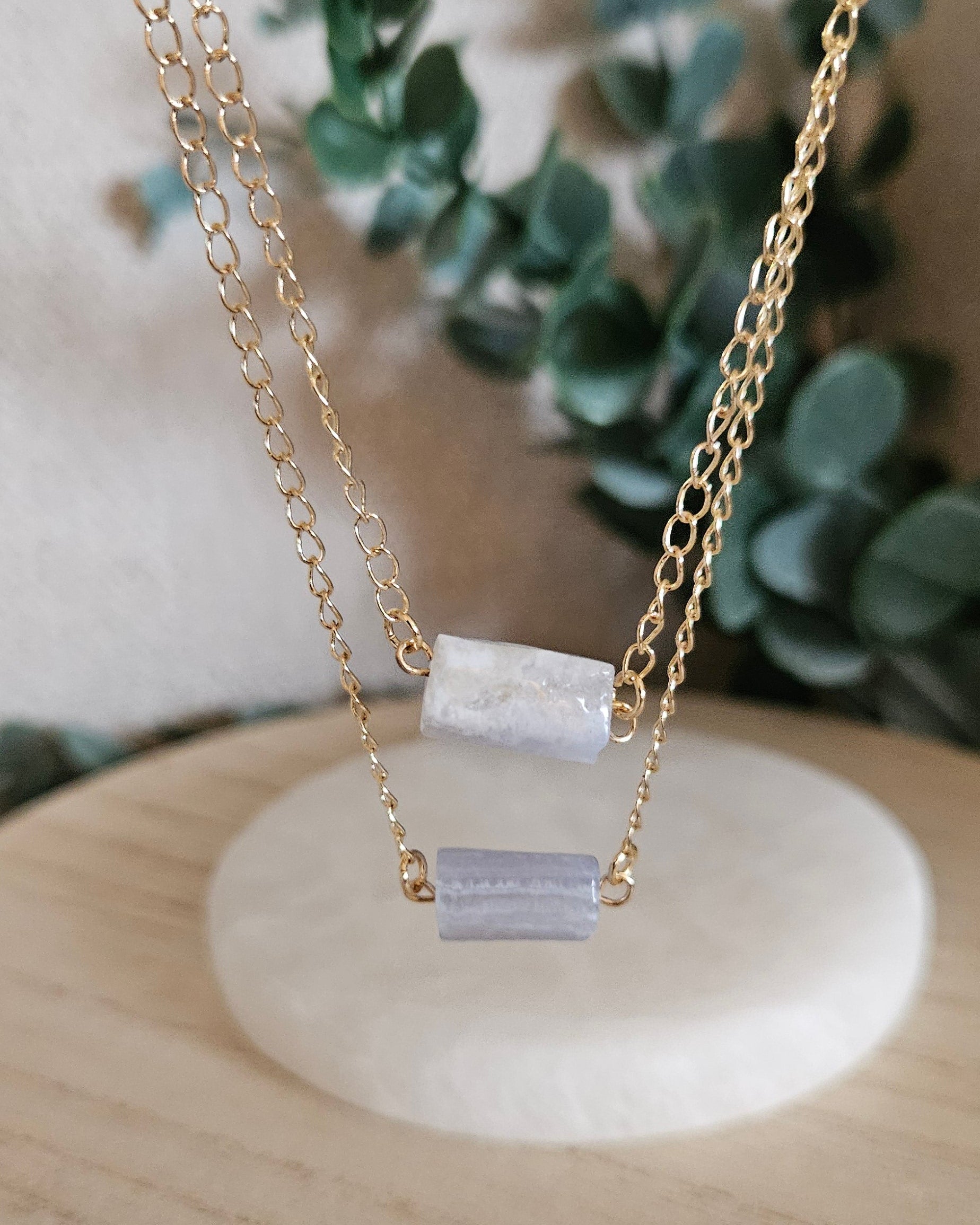Gold-plated double-chain necklace suspended above a selenite plate with two Blue Lace Agate stones