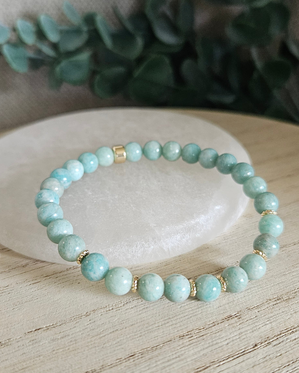 Amazonite Grace bracelet with blue-green gemstone beads and gold-plated accents styled on selenite with greenery behind it