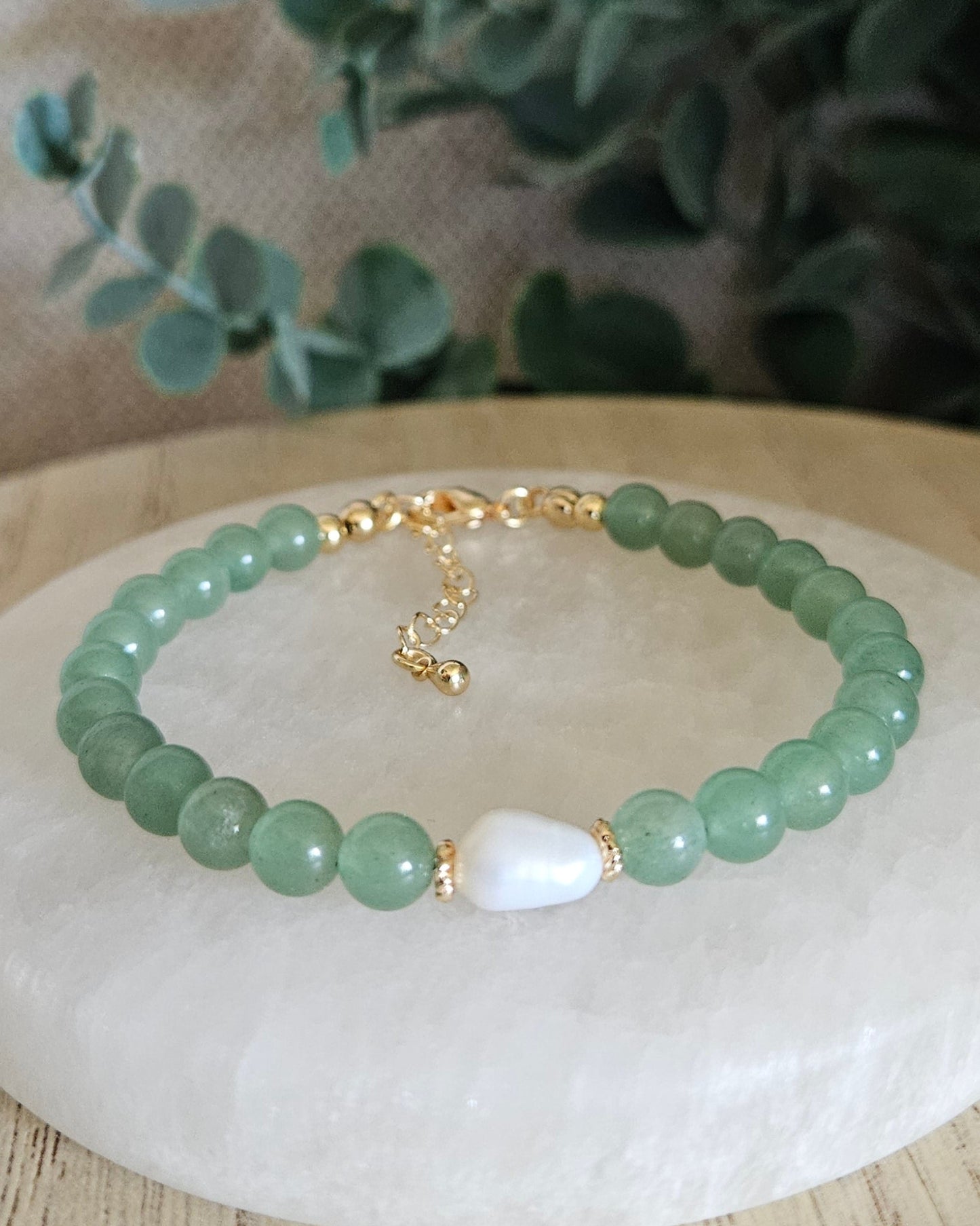 Green Aventurine Embrace bracelet with freshwater pearl focal and gold-plated accents displayed on a selenite plate
