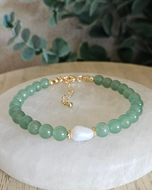 Green Aventurine Embrace bracelet with freshwater pearl focal and gold-plated accents displayed on a selenite plate