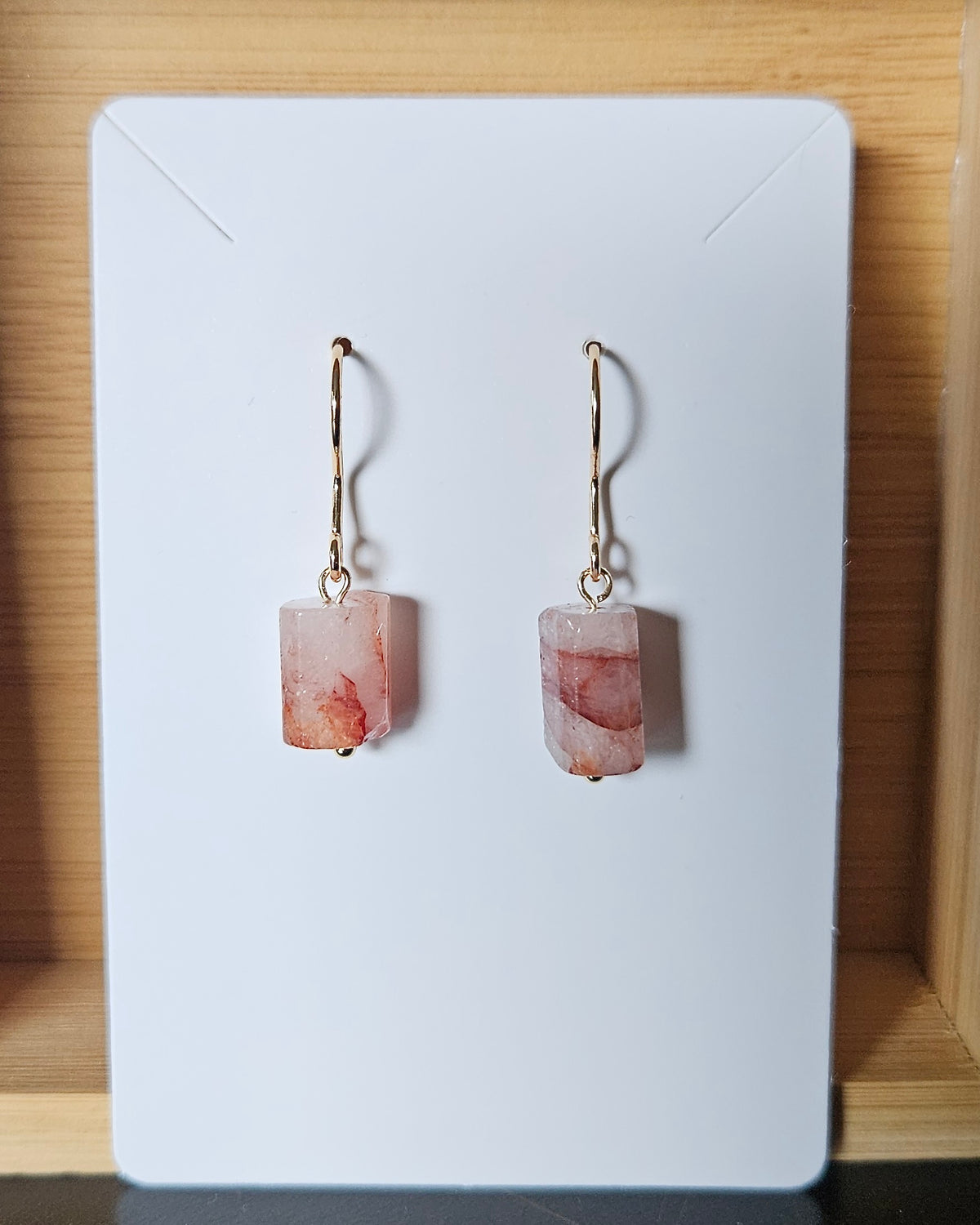 Handmade red hematoid quartz earrings displayed on a white earring card