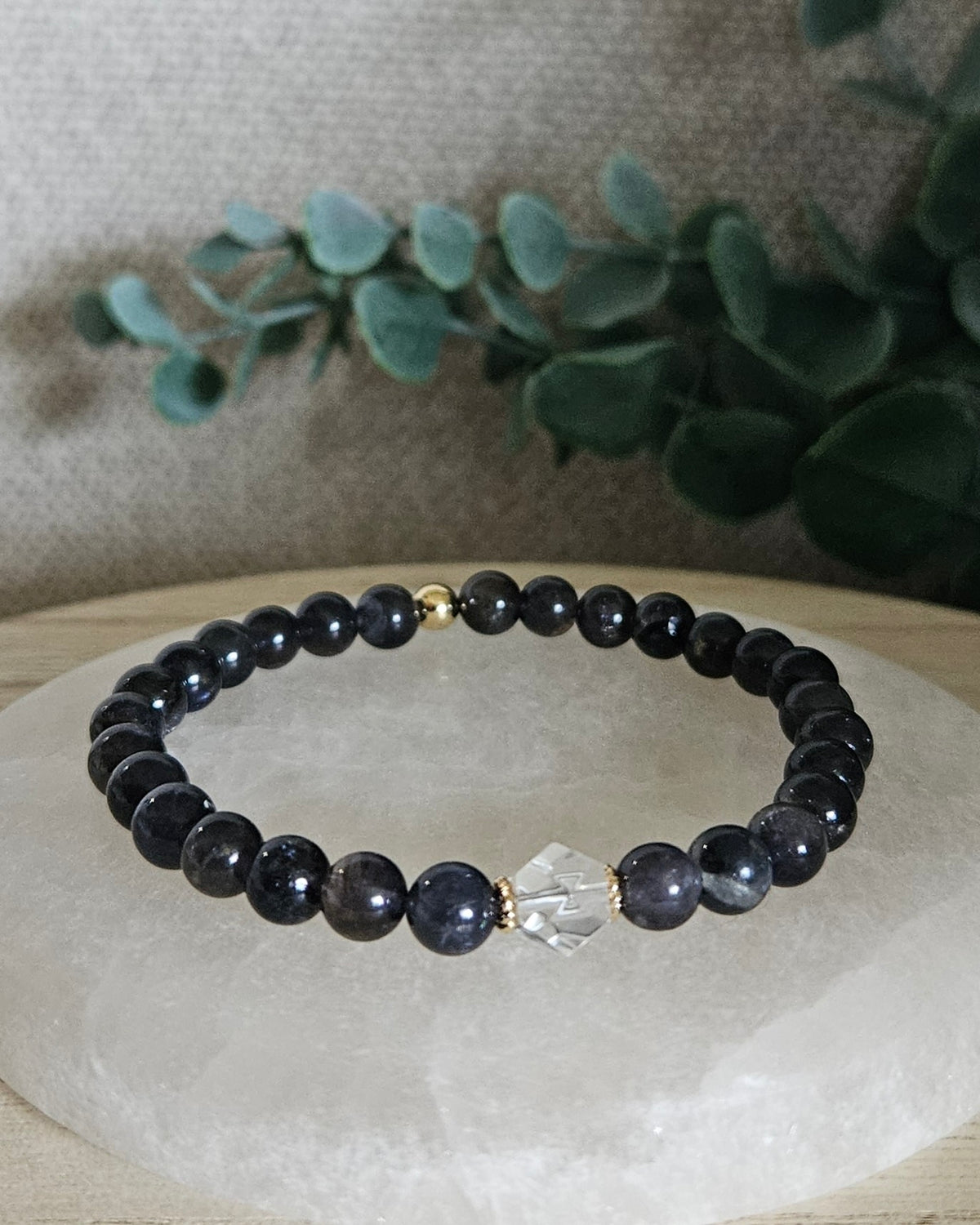 Iolite Still bracelet with 6mm dark blue gemstone beads, Clear Quartz hexagon focal and 14k gold-plated accent bead displayed on selenite