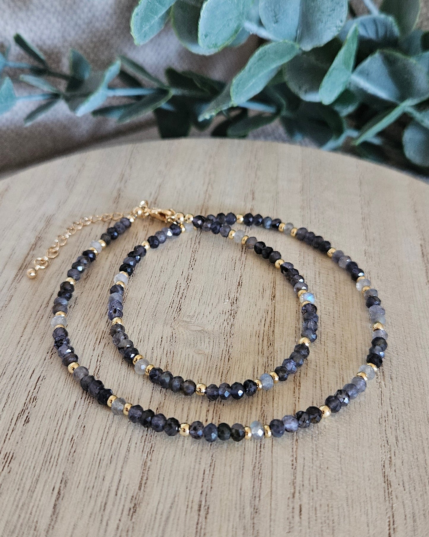 Iolite and Labradorite necklace loosely coiled on a wooden display with its clasp and extender chain visible