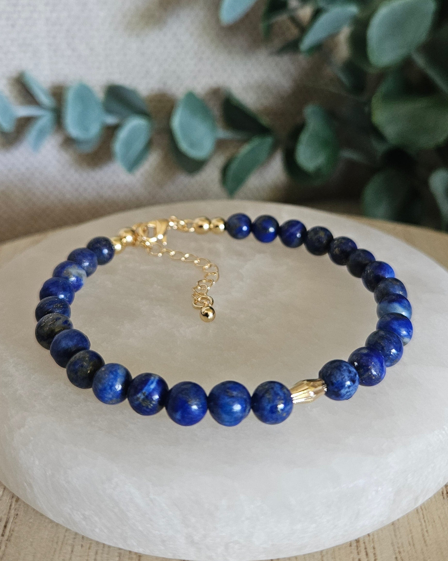 Lapis Lazuli bracelet with a diamond-cut gold-filled oval focal displayed on a round selenite plate