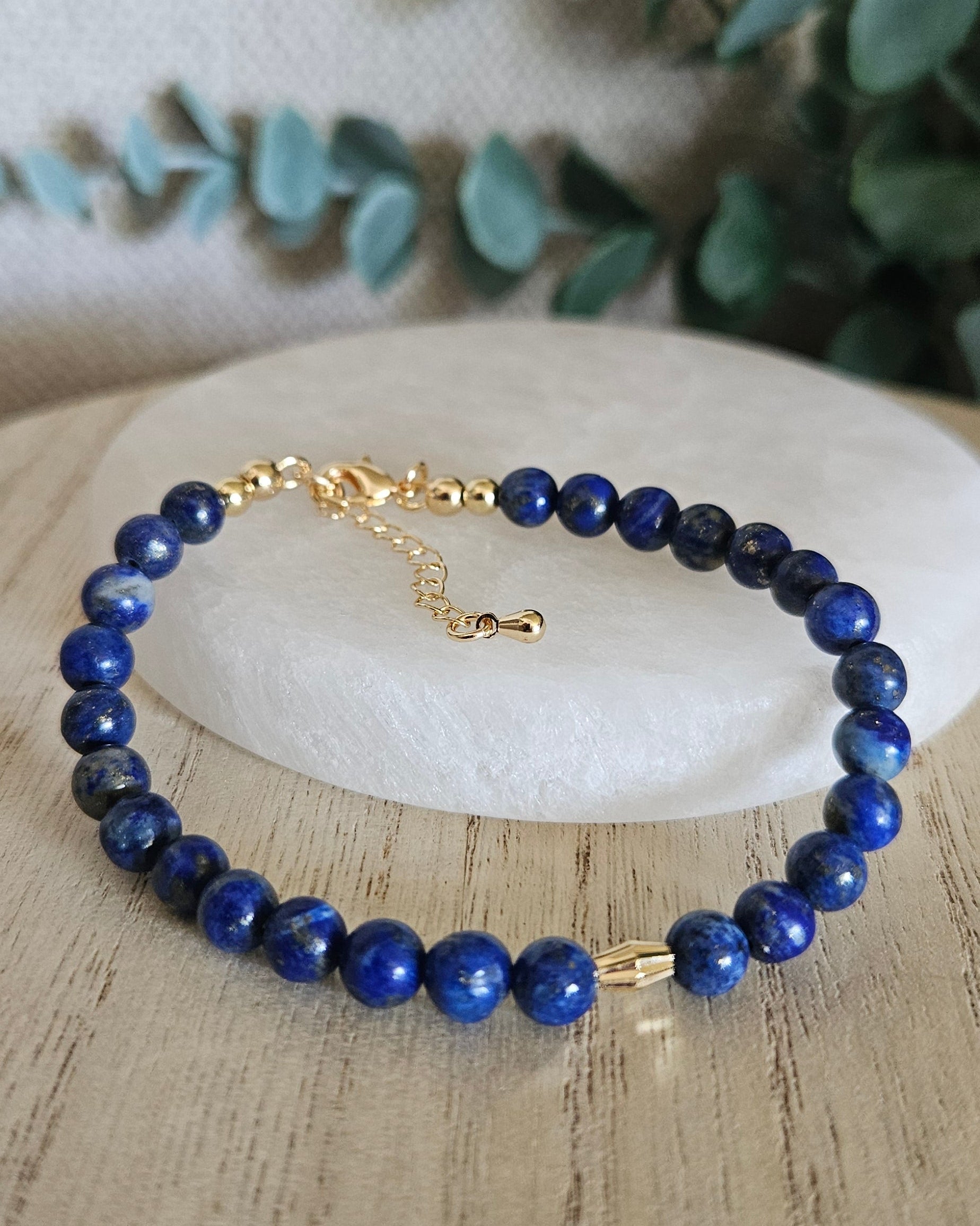 Lapis Lazuli bracelet arranged before a round selenite plate with eucalyptus in the background