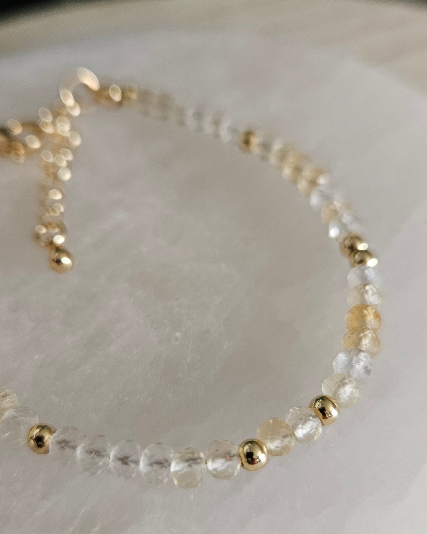 Macro close-up of pale-yellow faceted Citrine beads and polished gold-plated spacer accents