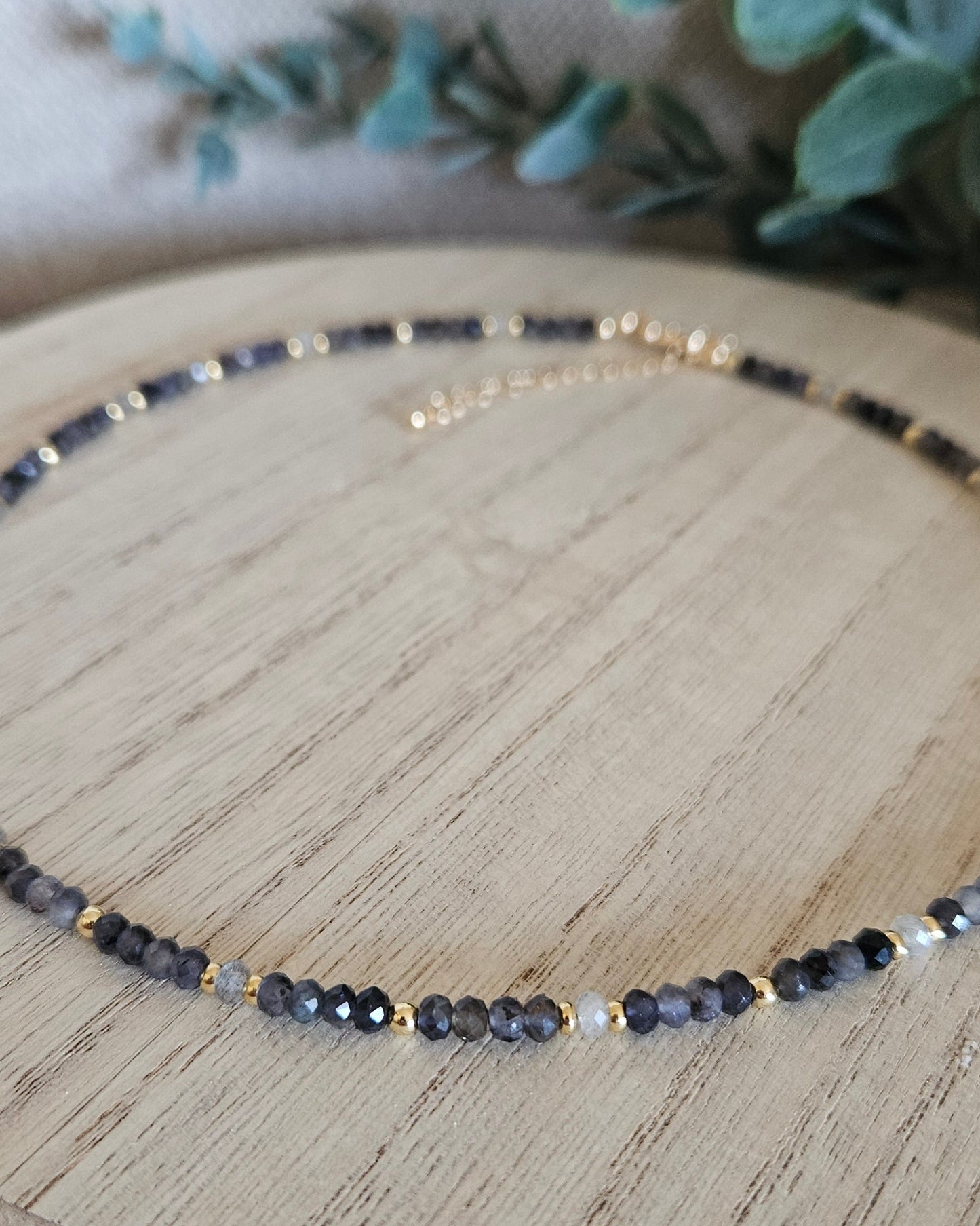 Macro view of dark Iolite, grey Labradorite and polished gold-plated accent beads