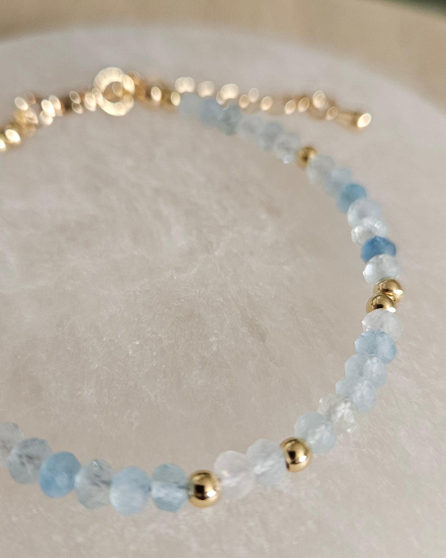 Macro view of faceted Aquamarine beads and polished gold-plated spacer accents