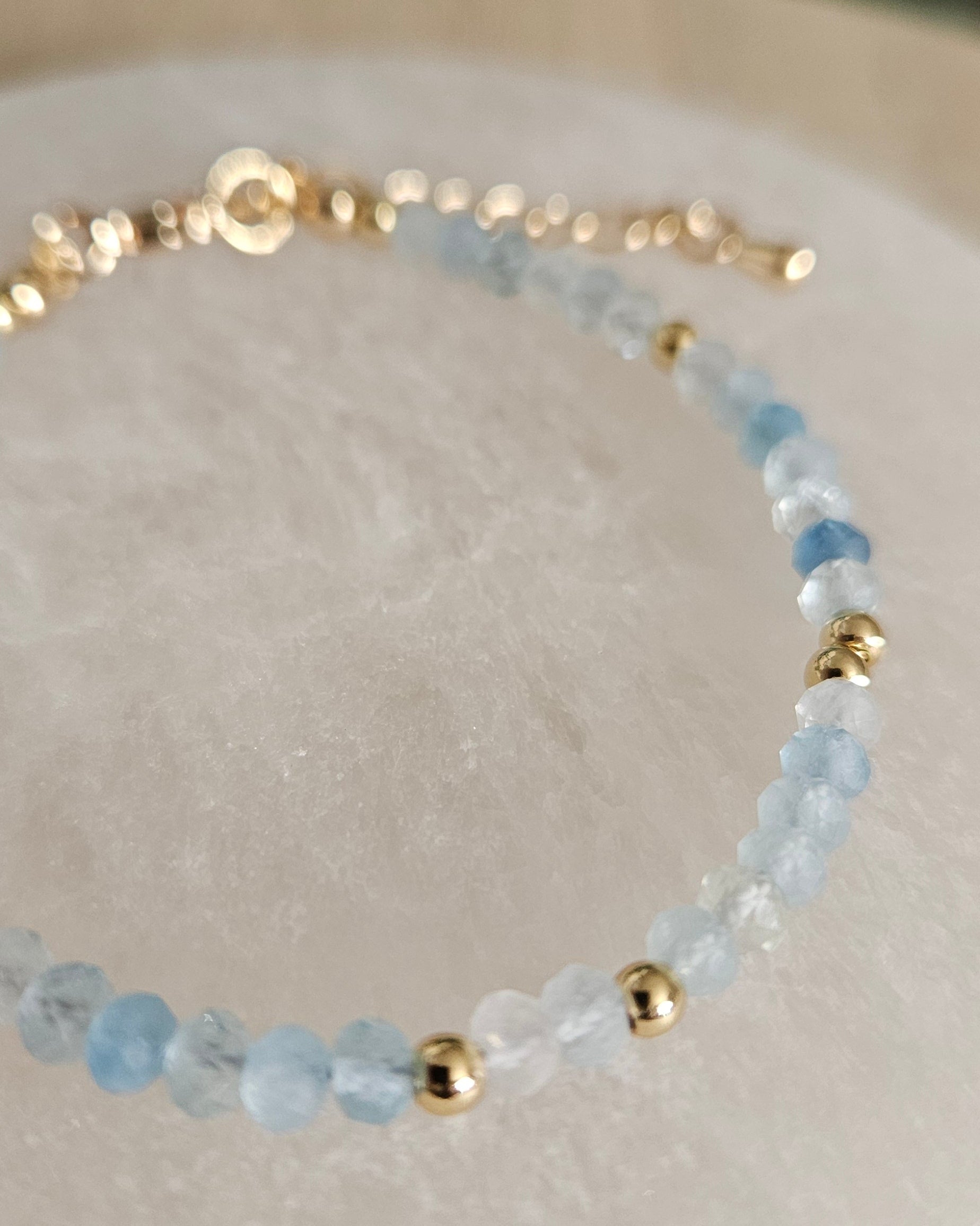 Macro view of faceted Aquamarine beads and polished gold-plated spacer accents