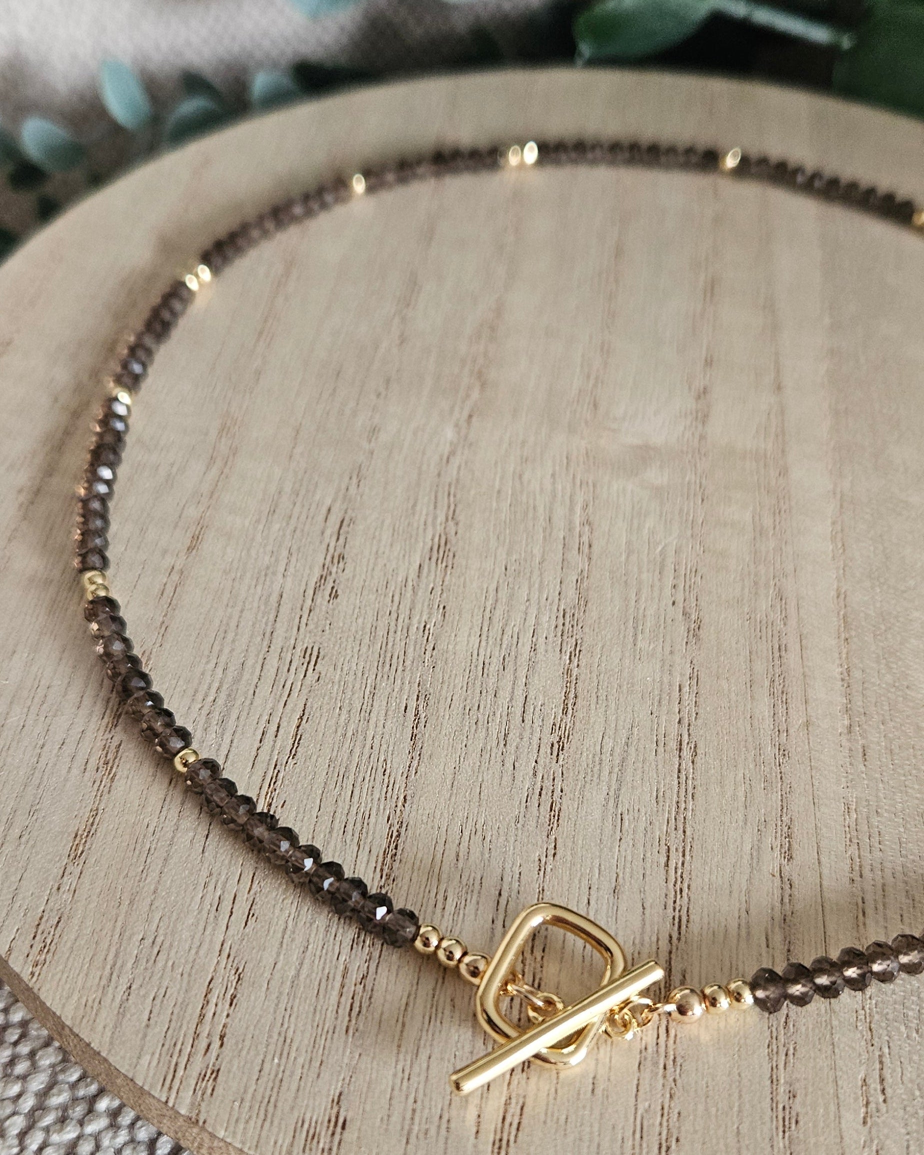 Macro view of the Smoky Quartz necklace showing its front toggle clasp and polished gold-plated accents