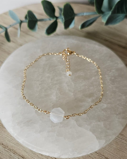 Moonstone Whisper bracelet laid flat on a selenite plate with 14k gold-plated chain, clasp and extender