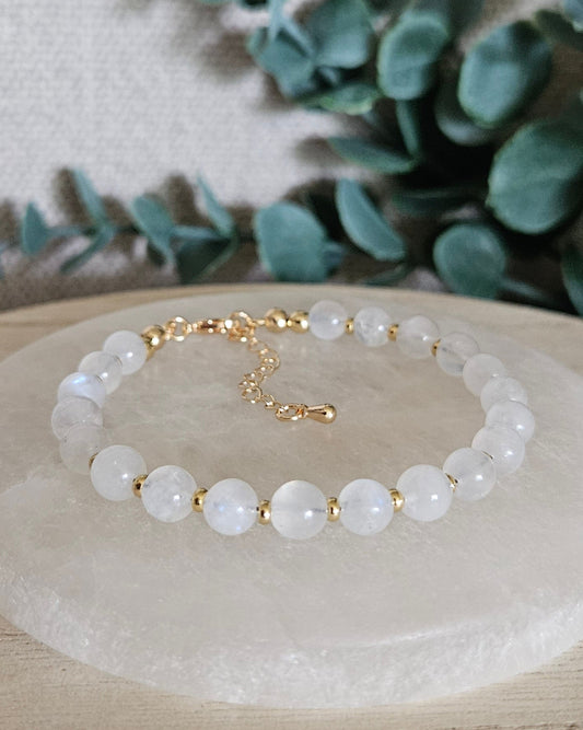Moonstone Echo bracelet with gold-plated accents and clasp displayed on a round selenite plate