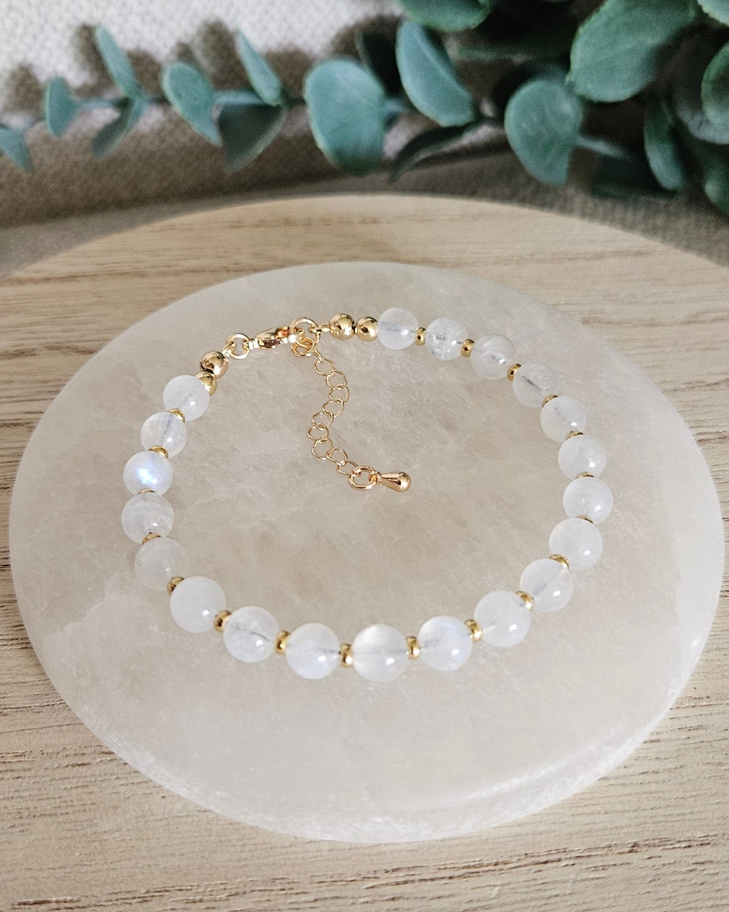 Overhead view of the Moonstone Echo bracelet with gold-plated clasp and extender chain on selenite
