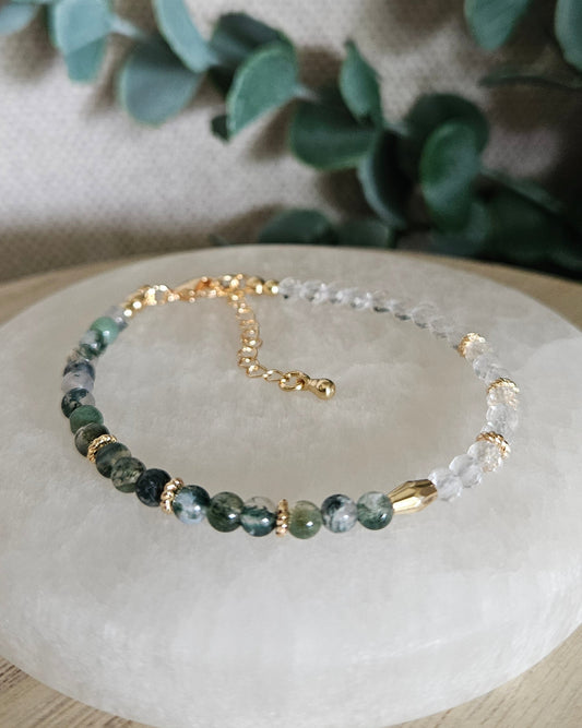 Moss Agate and faceted Clear Quartz bracelet with gold-filled accents displayed on a round selenite plate