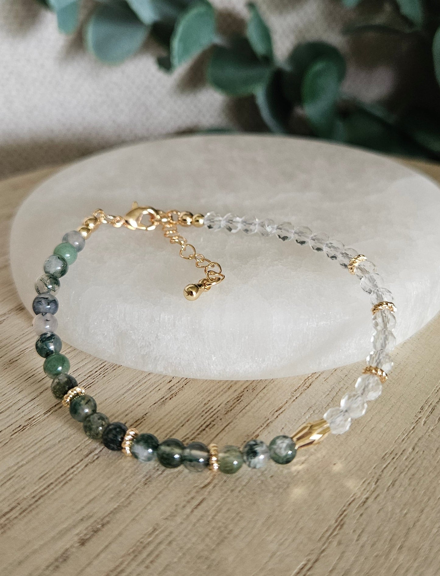 Moss Agate and Clear Quartz bracelet arranged before a selenite plate with eucalyptus in the background